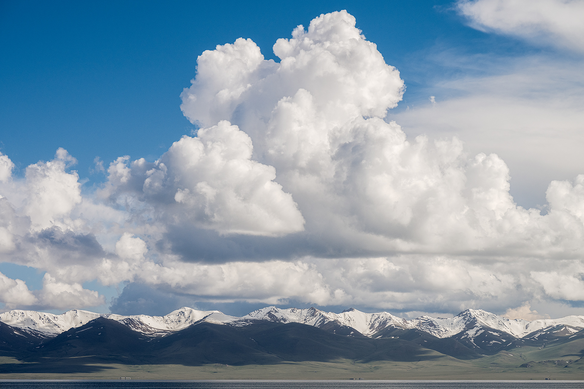 Travel photography in Kyrgyzstan at Lake Song-Kul, at an altitude of 3,000 metres. The photograph shows a cumulonimbus cloud formation above the mountains.