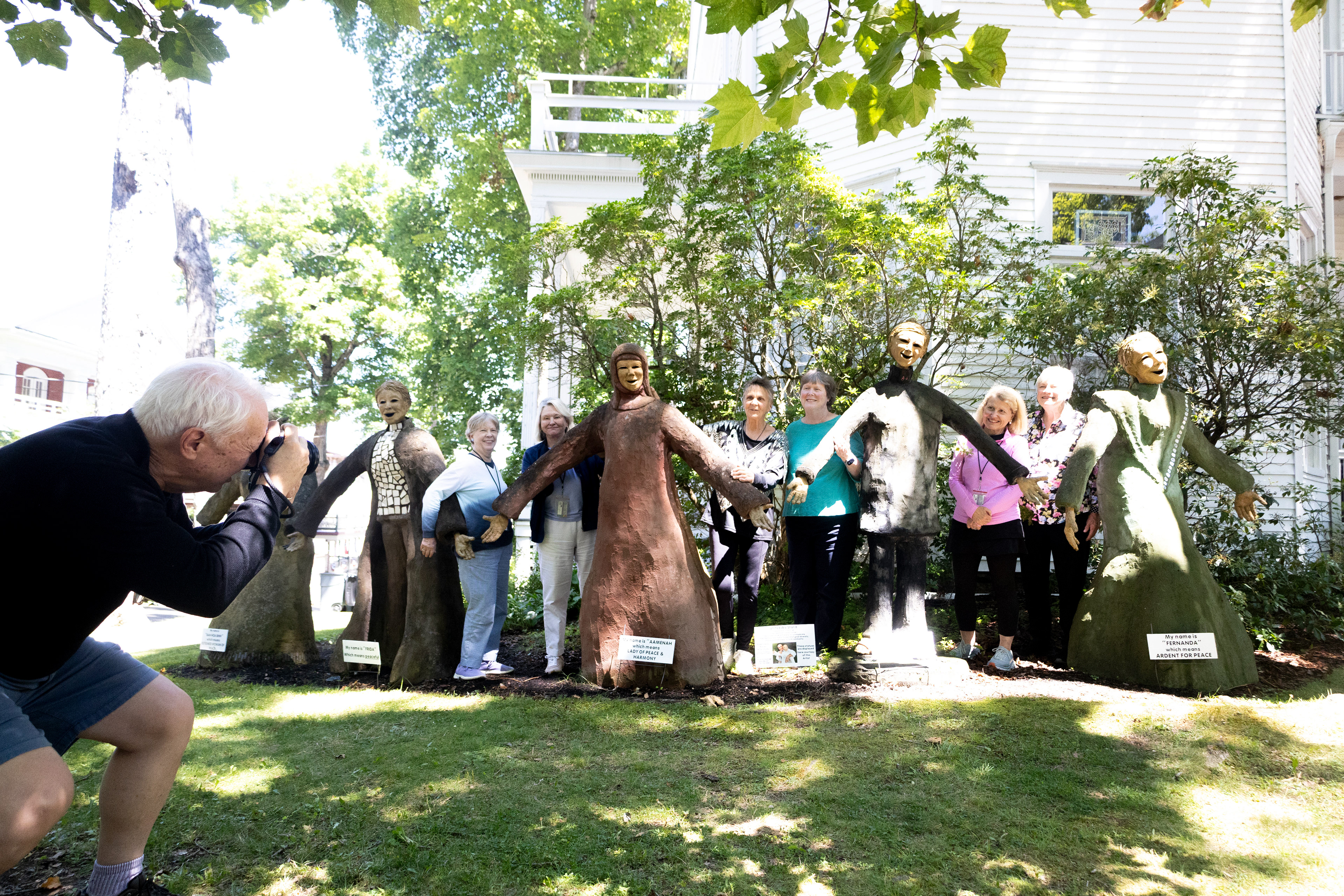 Artist Kirsten Engstrom, center, poses for a photo with admirers next to her sculpture piece, "United We Stand," in front of the Baptist House 