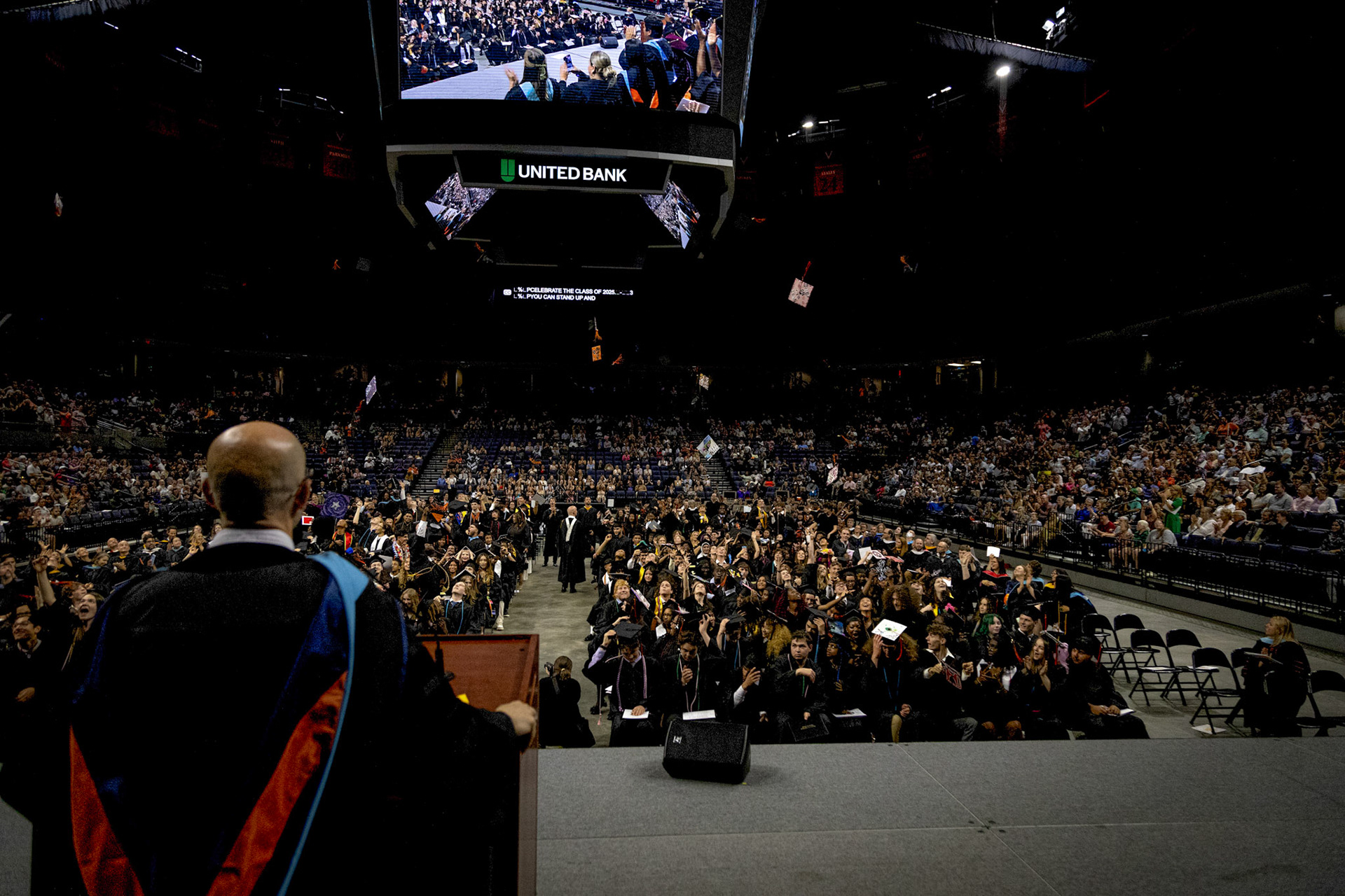 The Charlottesville High School principal, Justin Malone, looks out over the graduating class of 2025 as they throw their caps. John Paul Jones Arena, May 21, 2025
