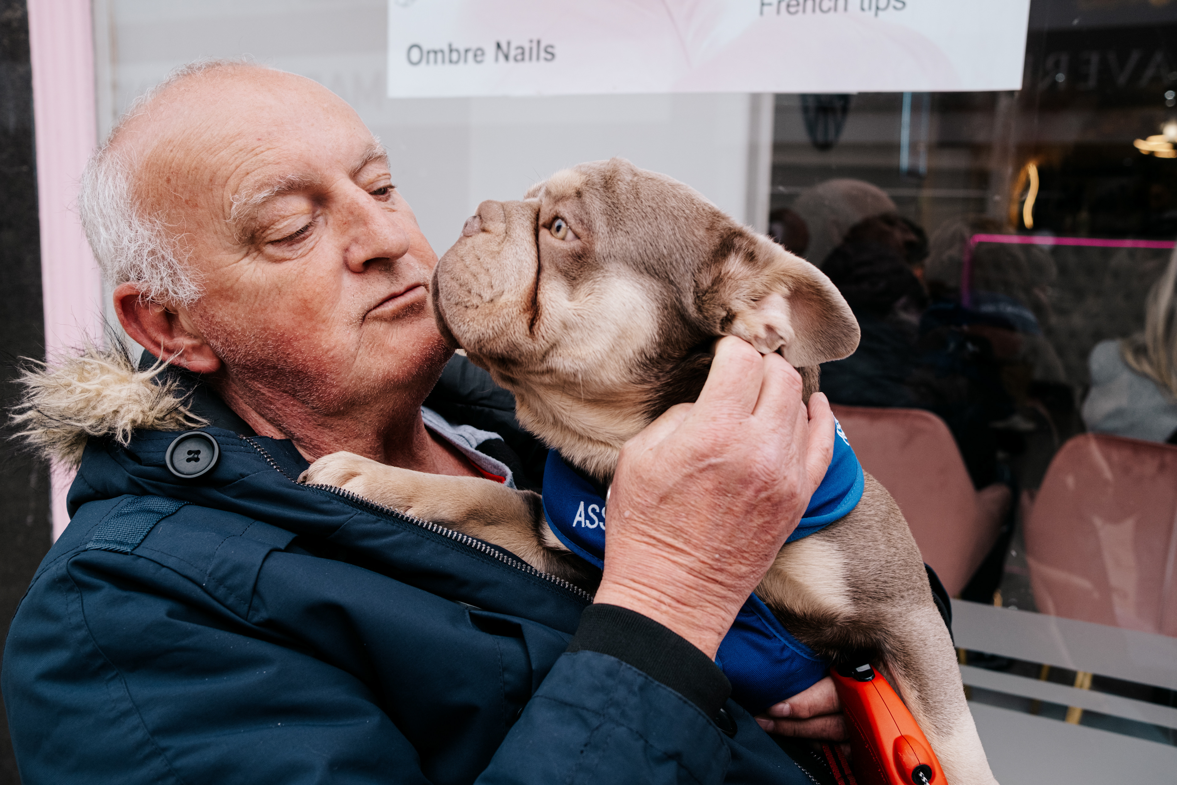 “The scooter’s hers. The dog’s hers. I’m just the driver.” Dave waited patiently for his wife outside the nail salon, seated on her mobility scooter. Beside him sat Bronson, her support dog, resting calmly on his lap. Between them, there was an easy companionship that made the wait feel lighter.