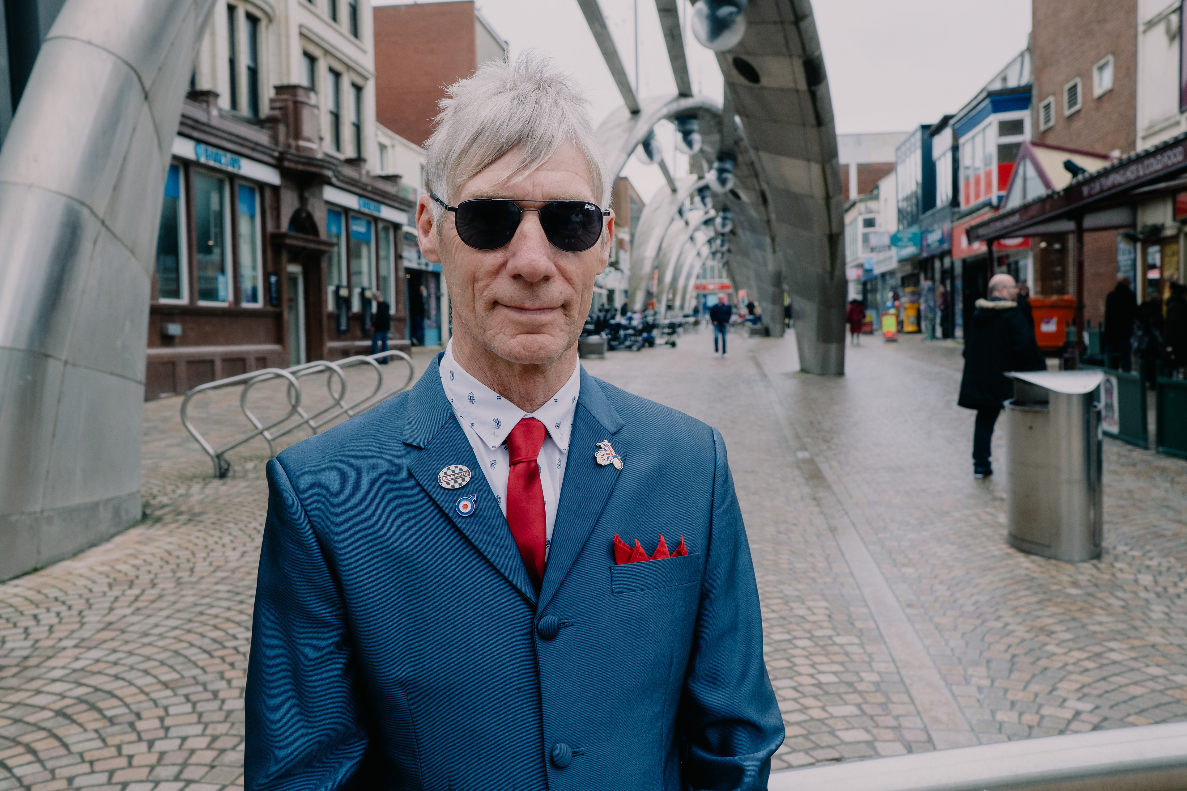 “Clothes are just another way of saying who you are.” Dressed in a sharp blue suit, with a red tie and pocket square precisely in place, Steve stood with the air of someone who knows exactly who he is. Every detail of his style carried intention. The ultimate Mod Father.