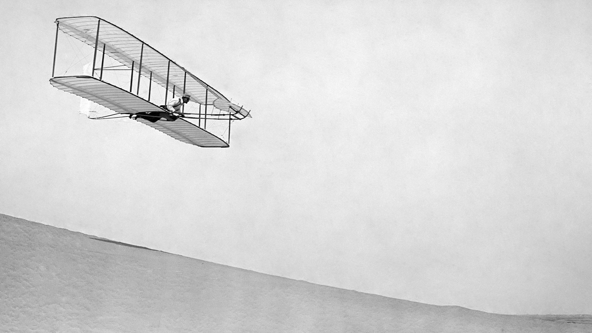 Wilbur Wright gliding down slope of Big Kill Devil Hill; Kitty Hawk, North Carolina, 1902.