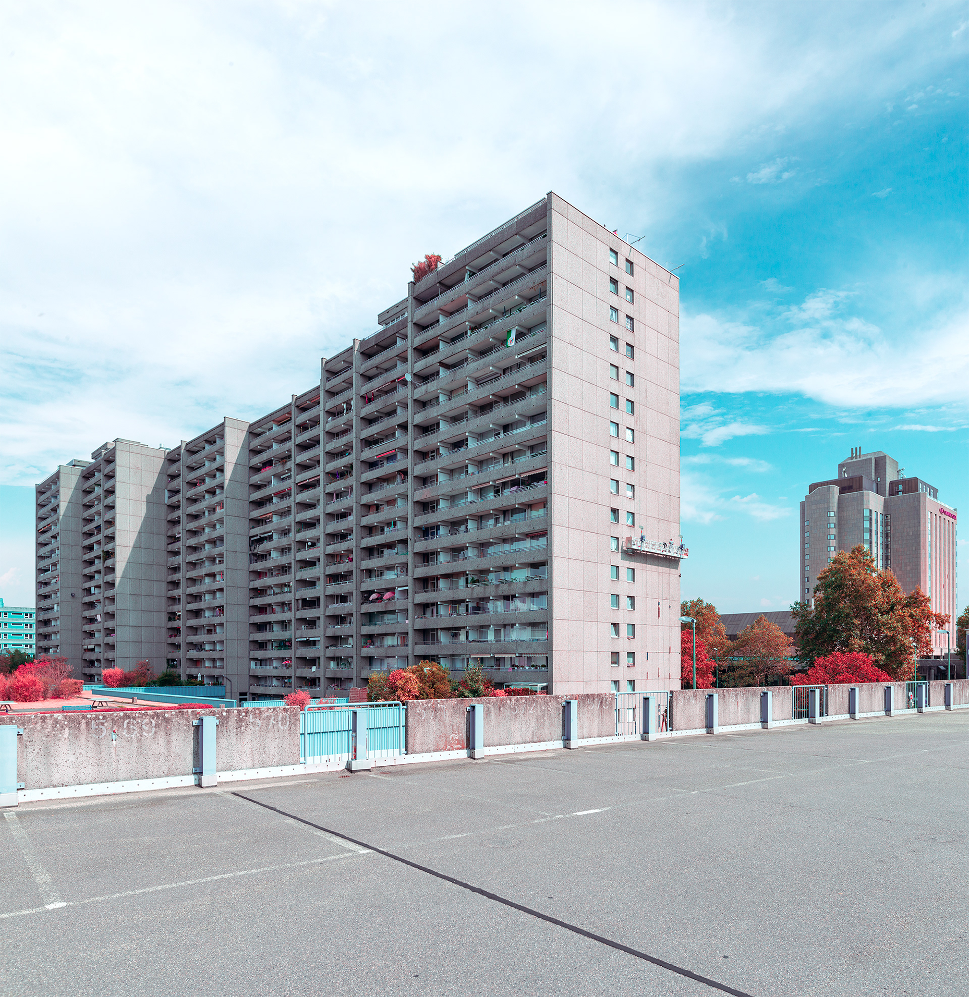 Parkplatz - Ein Nichtort     Die Vision der autogerechten Stadt hat sich am Düsseldorfer Hauptbahnhof eine eigene Ordnung geschaffen. Zentral gelegen erschließt das Parkhaus die nah gelegene Innenstadt. Die Beschleunigung der autogerechten Stadt trifft hier auf wehrhafte Mauern und Decken aus Stahlbeton. In diesem Komplex aus Parkgeschossen, Treppenhäusern, Fahrstühlen und Fahrbahnen kommt die Mobilität zur Ruhe und zum zeitweiligen Stillstand. Auf dem obersten Deck jedoch stellt sich eine seltsame und unbekannte Ahnung ein, denn schon lange parken hier keine Automobile mehr. Das Parkdeck, das dem Boden seine Funktion eingeschrieben hat, wird nun von Staub und Erde bedeckt auf der sich Pionierpflanzen ansiedeln.     Das Parkdeck ist ein Ort ohne Namen, Identität, oder Funktion. Grün schillernde Scherben, alte Plastikflaschen und die leblosen Fassaden des umliegenden Bertha von Suttner Platzes umschreiben die Zukunft dieses Ortes. Der Stillstand für den dieser Ort steht, manifestiert sich in der Infrastruktur. Die Fassade des Parkhauses  und der umliegenden Gebäude des Bertha von Suttner Platzes geben Auskunft über die Funktion des Raums.  Die Vielfalt findet sich an anderen Orten der Stadt wieder. Der Bertha von Suttner Platz ist Transit,- und Verwaltungsraum und die umliegenden Gebäude erfüllen ihre monofunktionalen Aufgaben. Als Besucher wird man mit der subversiven Macht der Raumführung konfrontiert. Der Körper wird gleichsam gezwungen den Raum und seine Grenzen zu erfahren und sich einen Ausweg aus diesem verwirrenden und unwirtlichen Raum zu suchen. Die Vorstellung den Raum neu zu definieren und bestimmte Eigenschaften auf diesen zu projezieren, scheiterte an der Vielfalt der Gesellschaft. Denn diese ist keine homogene, funktionale Masse die sich in Beton gießen lässt.    Neben der unmittelbaren Leere dieses Ortes sind die Grenzen relativ unsichtbar. Denn die Ströme die von der Infrastruktur ausgehen, kommen als Wellen in den unteren Parkgeschossen an. Die Flut der Mobilität scheint sich aber auf dem obersten Parkdeck an Kraft zu verlieren und gänzlich zu versiegen. Ähnlich wie ein mächtiger Strom, der seine Energie allmählich verliert, wird die Energie der Mobilität durch neue Kanäle, Wasserstraßen und Bäche geleitet. Zwar ist das Automobil am Zenit seiner Macht, aber zu welchem Preis?    Die Präsenz des Automobils in der Gegenwart, das den städtischen Raum für sich beansprucht, wird an diesem symbolischen und charakteristischen Ort aufgehoben. Ein paradox anmutender Zustand der keinen klaren Standpunkt zu vermitteln vermag. Zwischen glorreicher Vergangenheit, Gegenwart und Zukunft ist dieser Ort eine Möglichkeit einen ausgedehnten und einzigartigen Moment zu vollziehen, in dem die Stadt wieder dem Menschen gehört.  - Neben dem Hauptbahnhof habe ich einige Parkhäuser und Parkplätze in den nahgelegenen Stadtteilen dokumentiert -