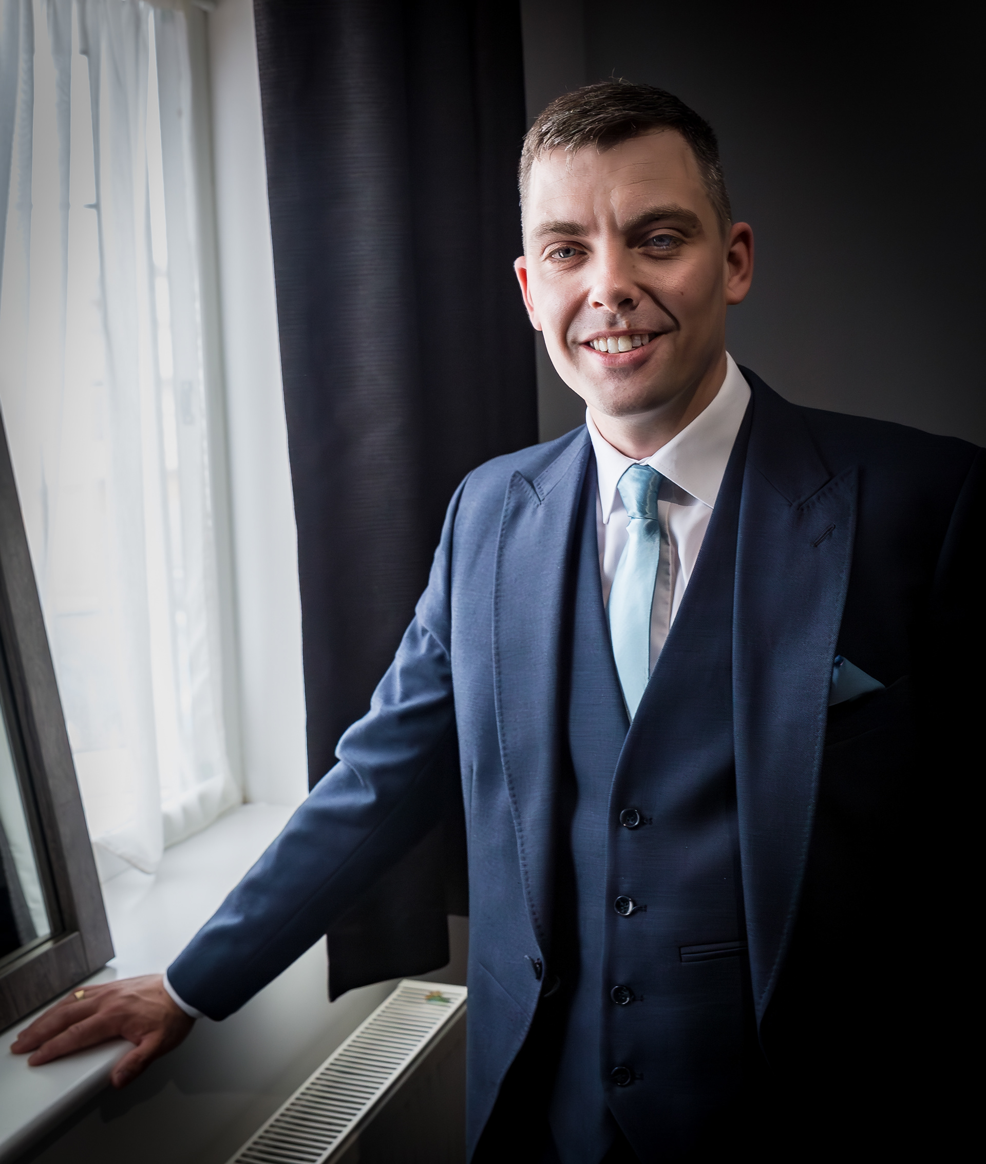 Groom posing by window by The Multi Media Market Wedding Photography in Dudley.