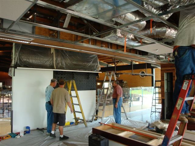 Dan Hoag, (blue shirt) owner of Eagle Wings Iron Craft begins the O gauge overhead install. P&P’sBob Field (red shirt) assists.