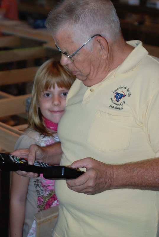 Bob Cowles two hands the controllers as grace watches.