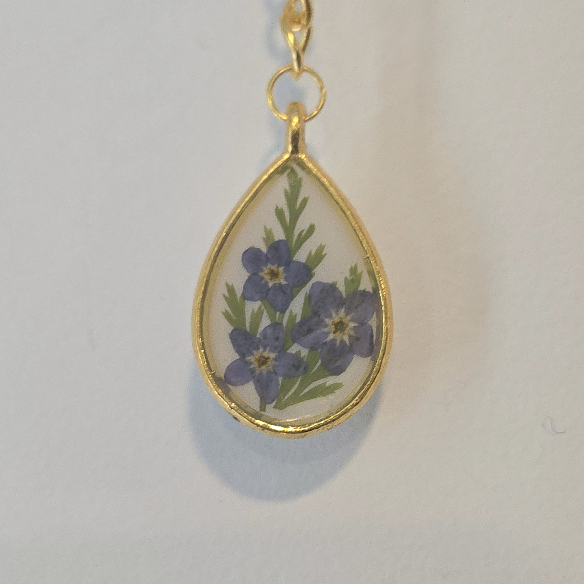 23. forget-me-nots in white teardrop, gold frame