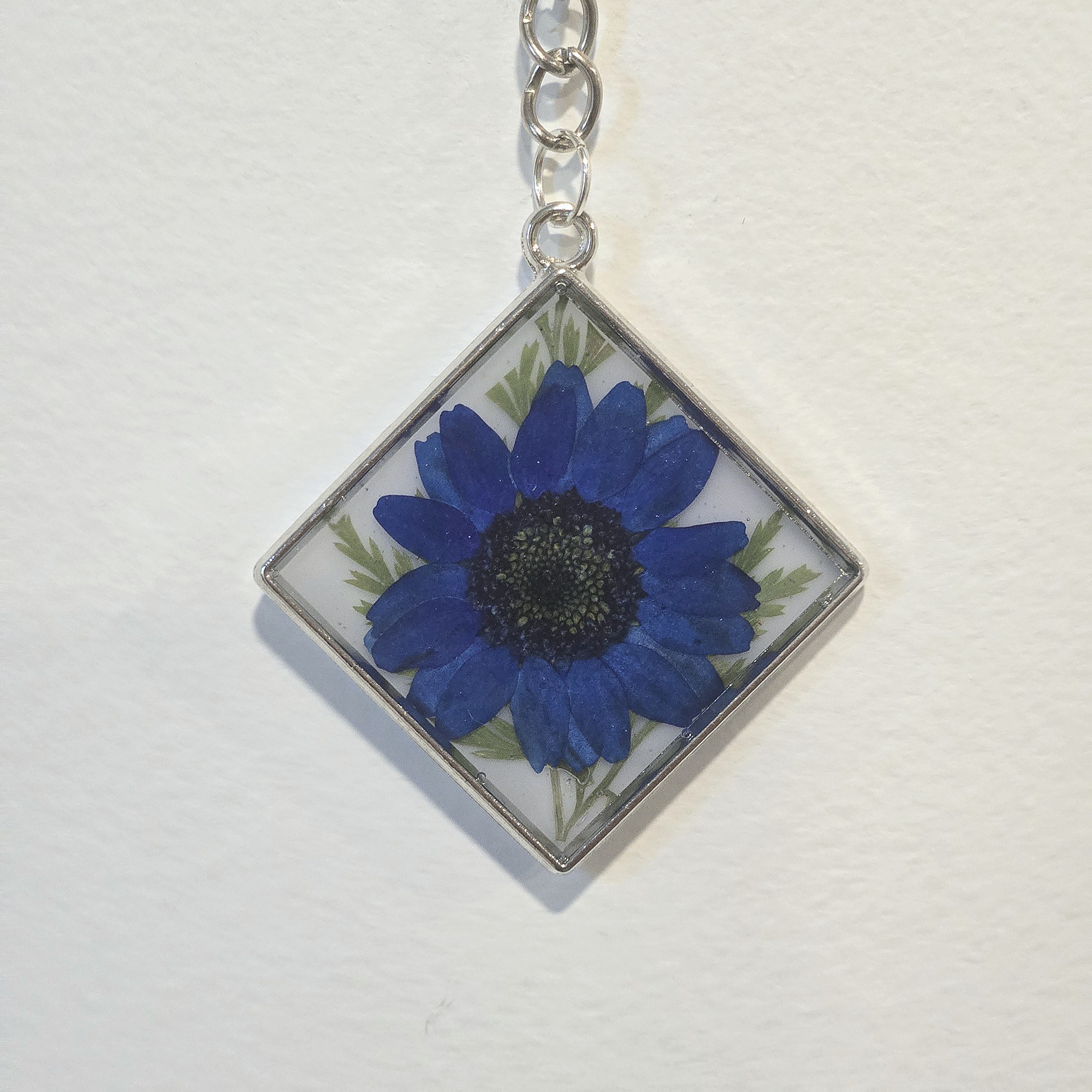 15. blue daisy in white tilted square, silver frame