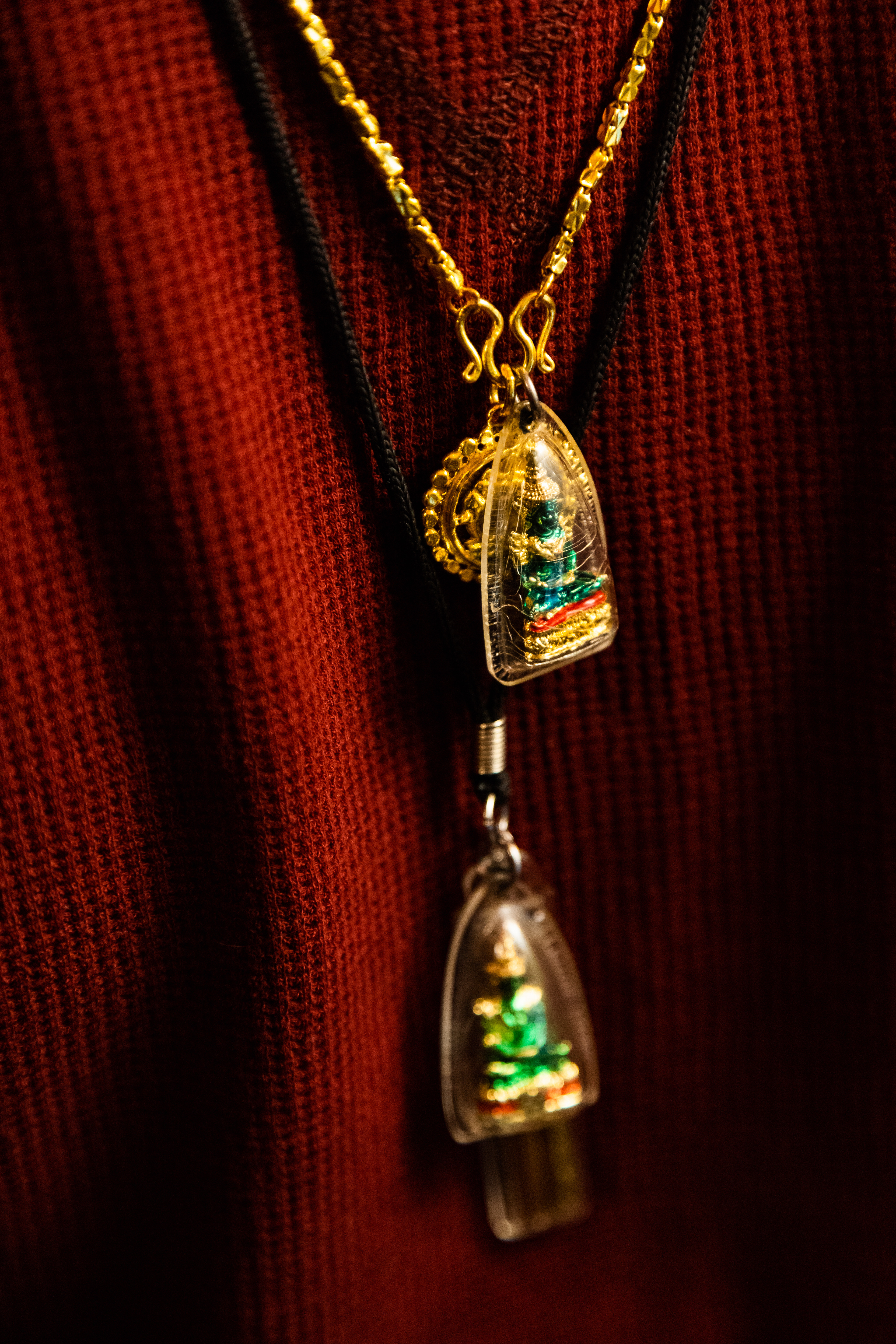 Gold necklaces featuring replicas of the Emerald Buddha, an important religious figure in Laos, and a Takrut inscribed with prayers, hang from the neck of Whon Phrakousonh, a business partner involved in the Wisconsin-based Laotian food business Sap-Sap, on April 14, 2021 (Photo by Brian Huynh)