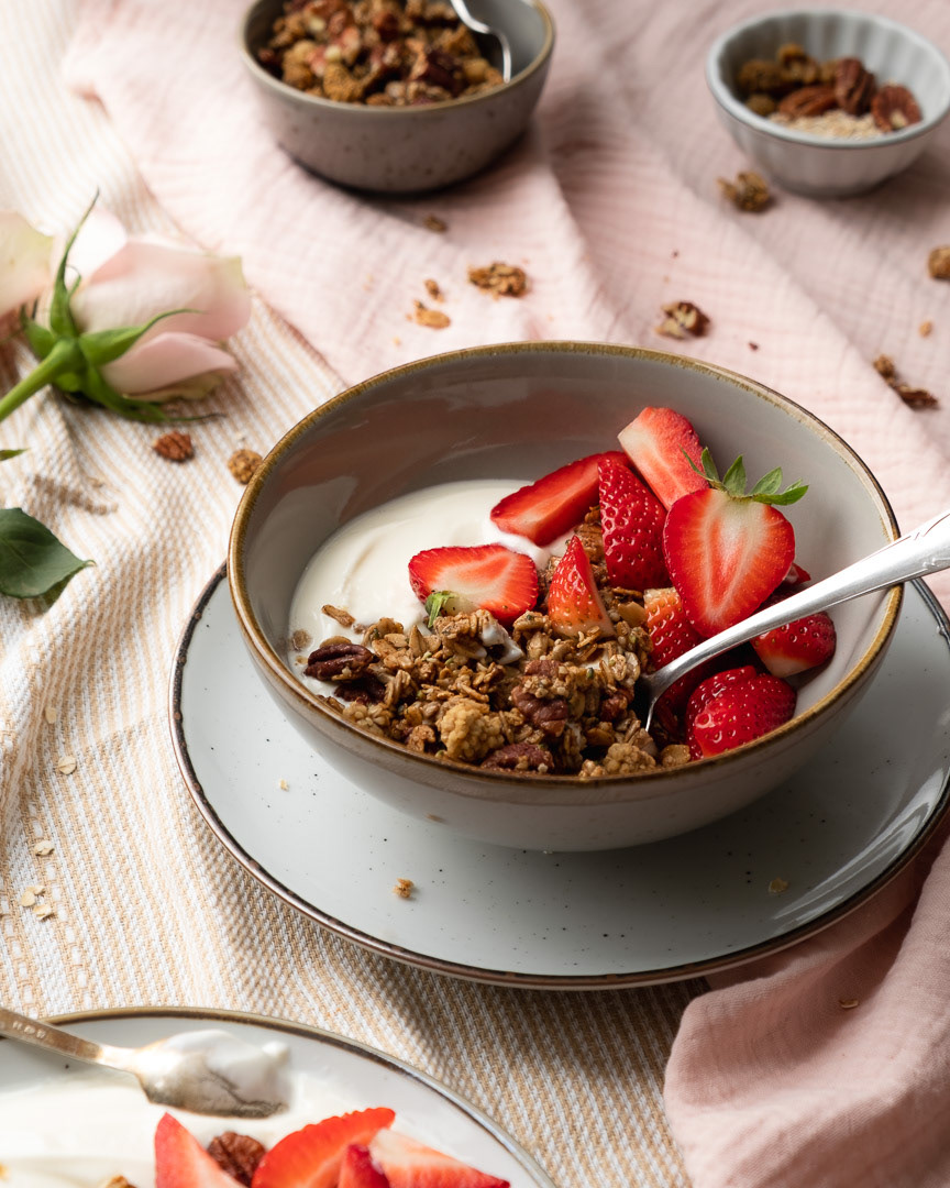 Kom met yoghurt, granola en aardbeien op een pastel achtergrond met servetten restaurantfotografie
