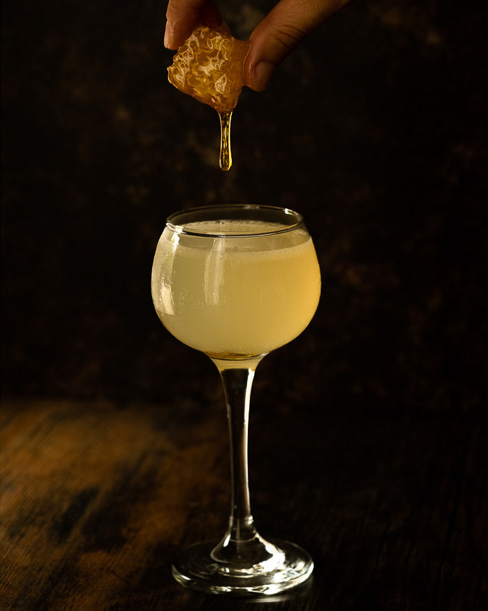 Honingraat die uitgeknepen wordt boven een cocktail cocktailfotografie Groningen