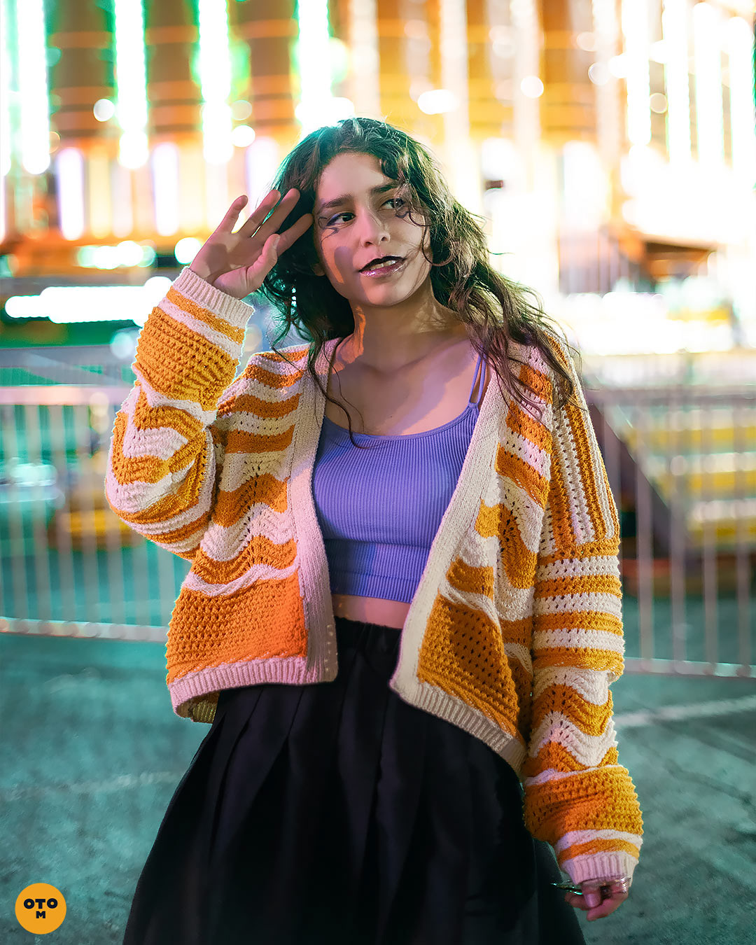 girl standing in front of UFO ride at carnival, neon lights photoshoot with emitela and otrominuto