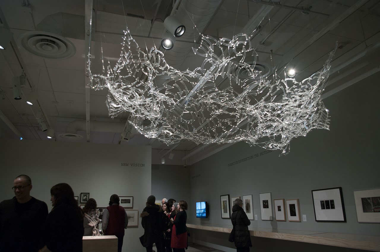 a plexiglass artwork of arrows hangs from the gallery ceiling