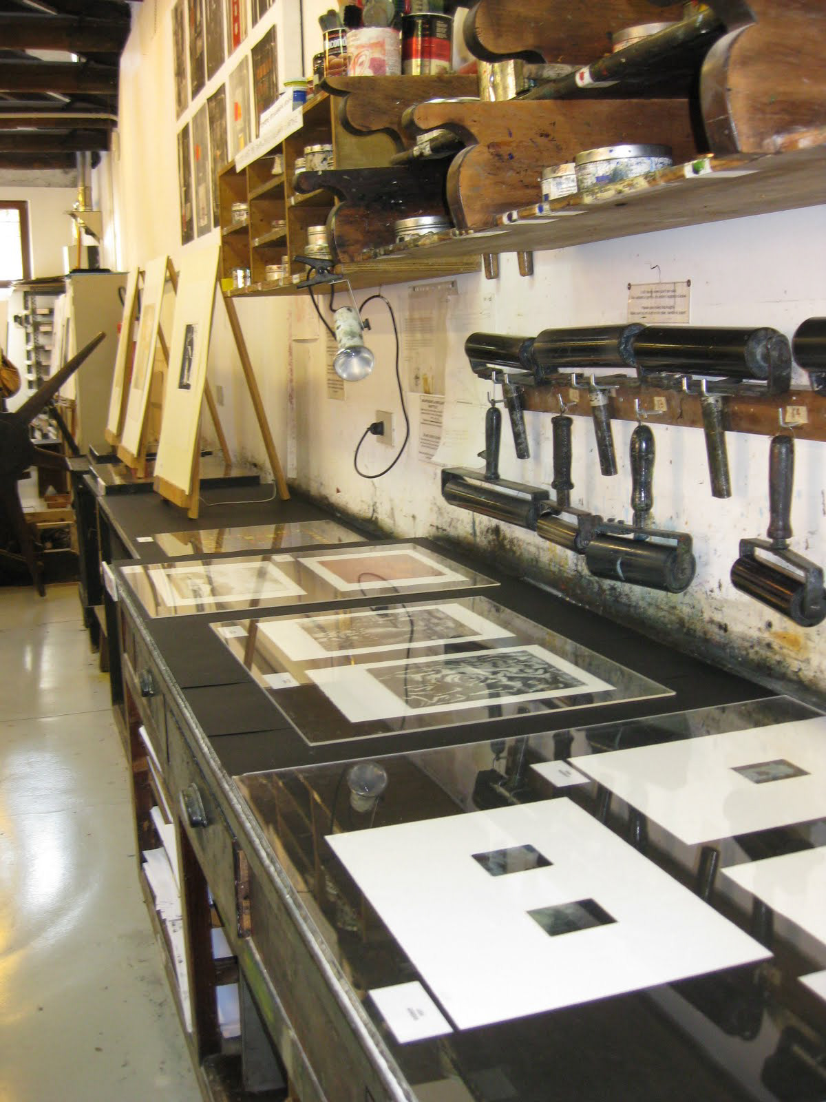 Prints from students and artists alike on display in front of rollers used for inking plates.