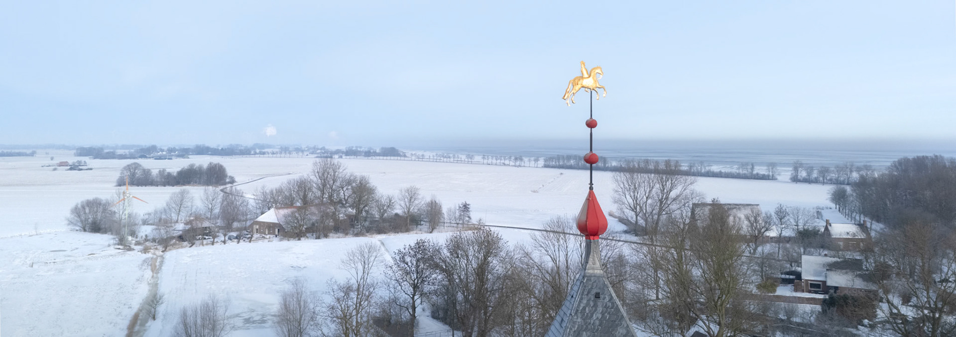 A golden horse-and-rider weather vane is on the church tower of Uitwierde.