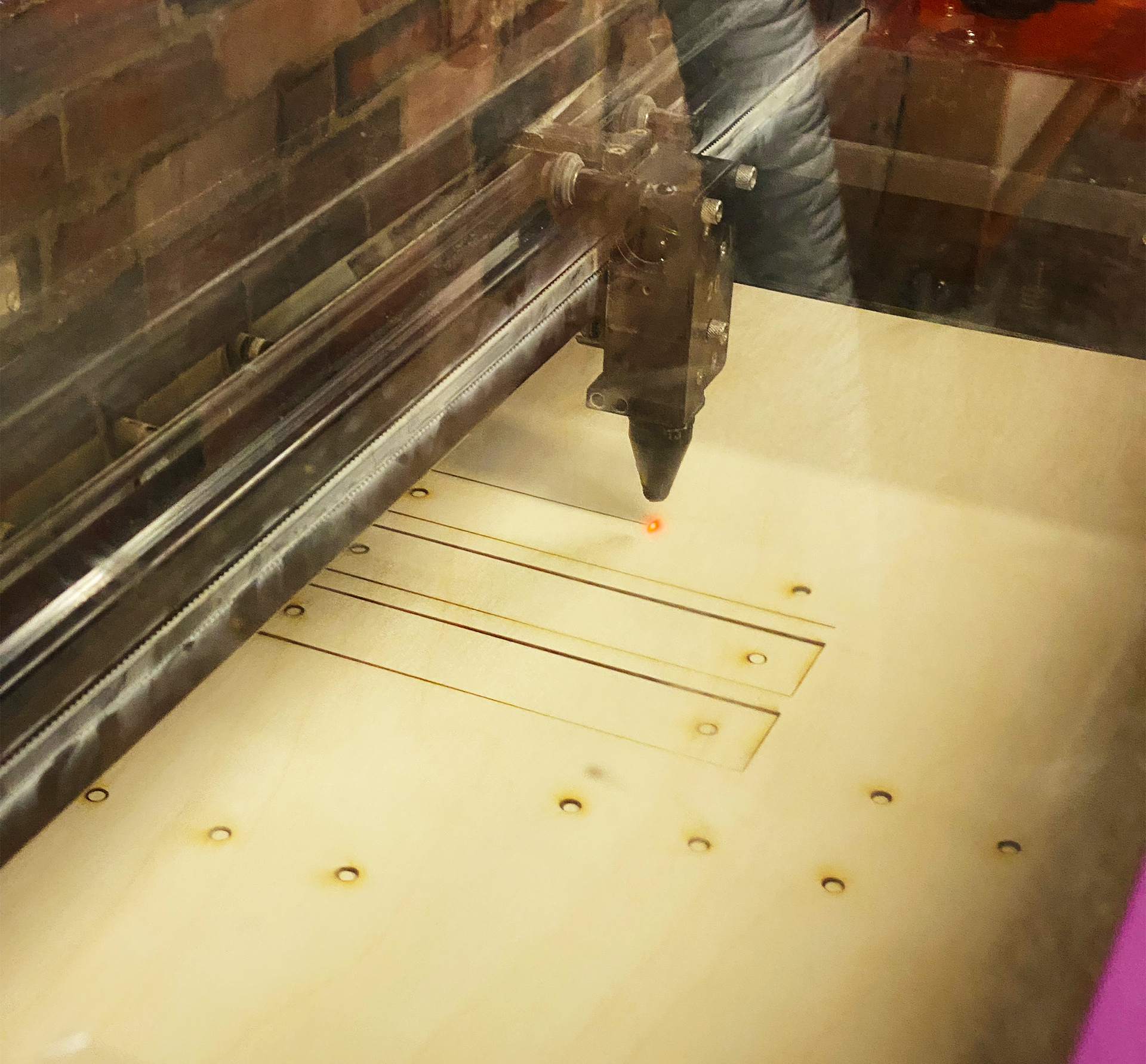 A laser cutting the link pieces from a piece of plywood.