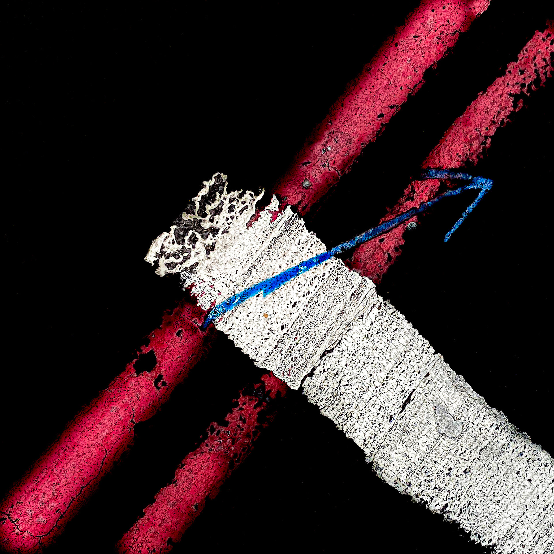Bromptom Road, Knightsbridge, London. Walking everywhere in the urban environment underfoot there is a free 'art show'. Hard surfaces are painted with markings indicating services etc. below, or for controlling traffic and pedestrians.  This photograph taken in August 2020 has been composed to create an abstract image made up of triangles and lines which echo the blue painted arrow.