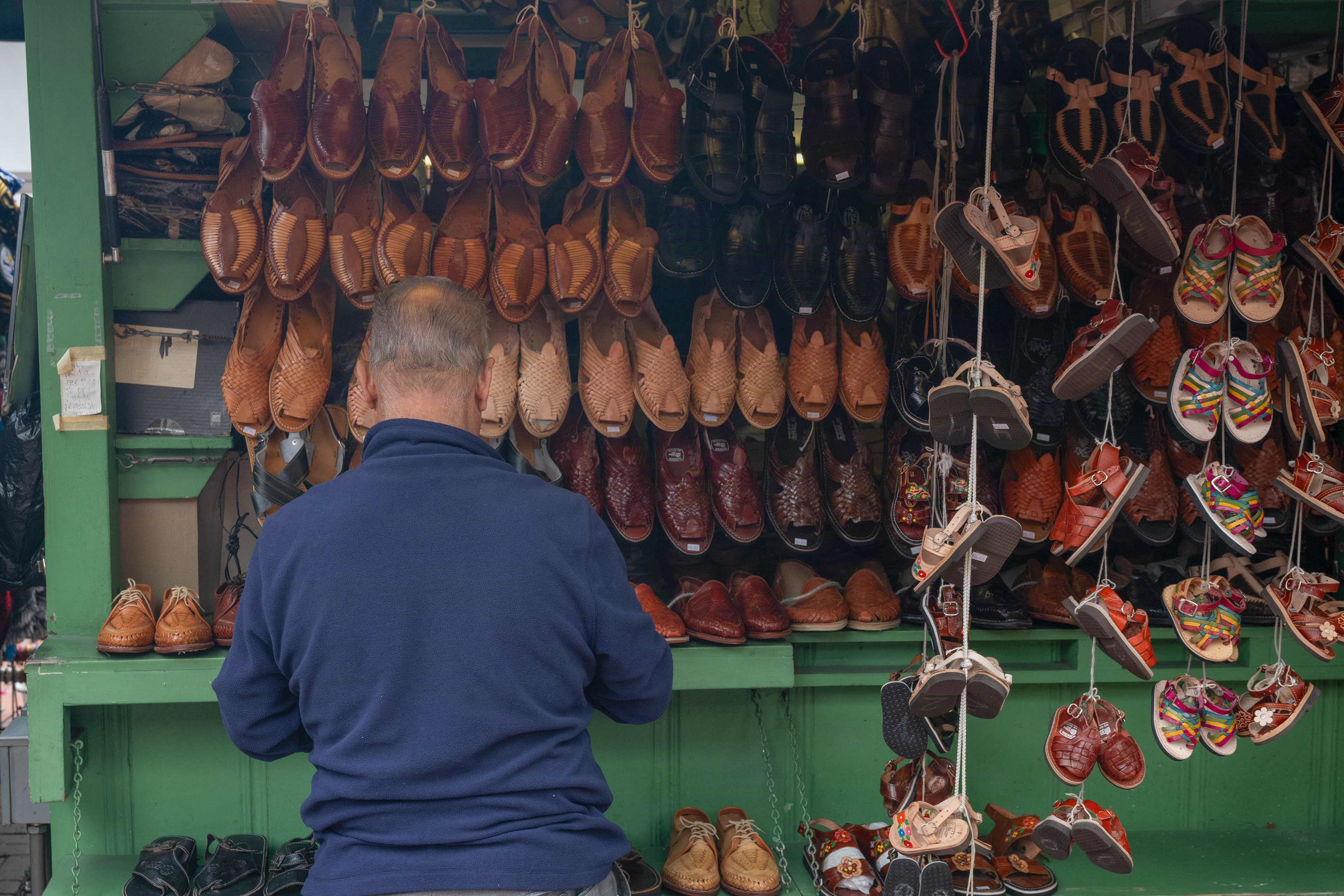 he vendor of the leather shoe store checks the pairs for check before he greets with visitors on a cloudy Sunday