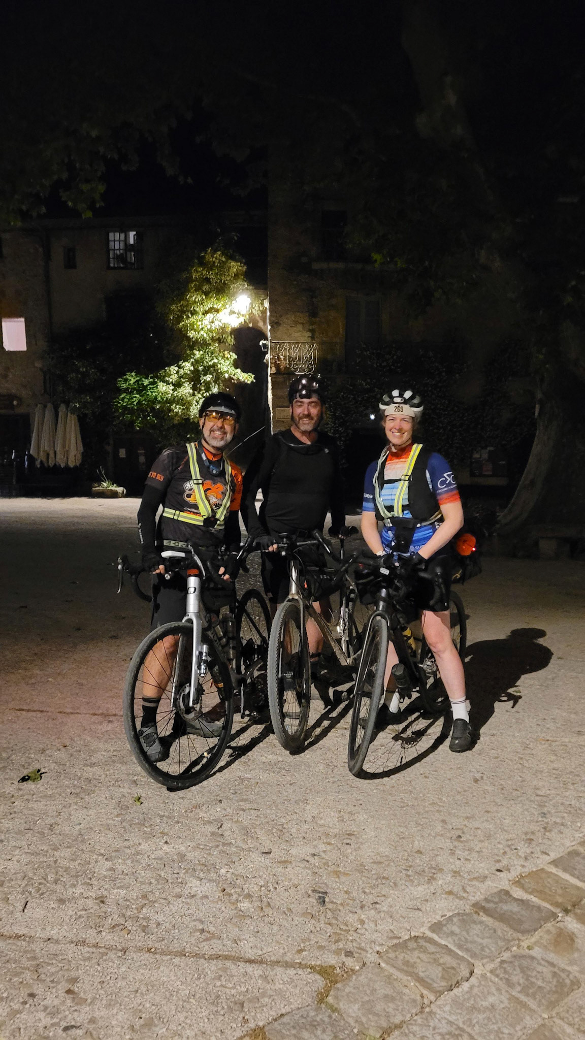 Photo de Eric, Nico et moi, tous les trois en habits de cyclistes, avec nos vélos. Sur une place de St Guilhem le Désert, de nuit