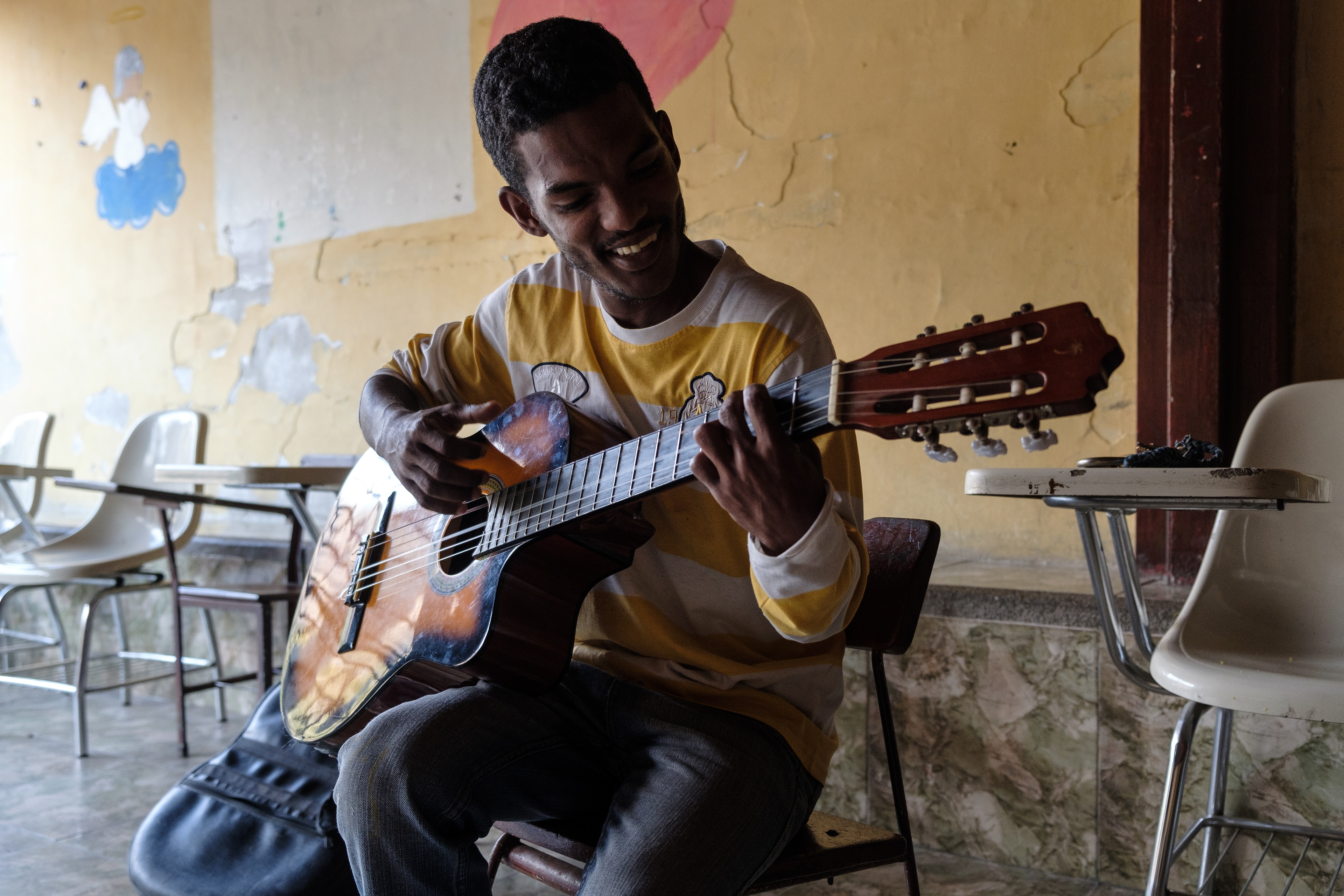 Duglas Alexander Mendoza, plays the guitar at the youth center in The community of San Isidro in Petare. The guitar is missing a string but they haven't been able to repair it. He still uses it to teach the choir at the church. Caracas April 5, 2019