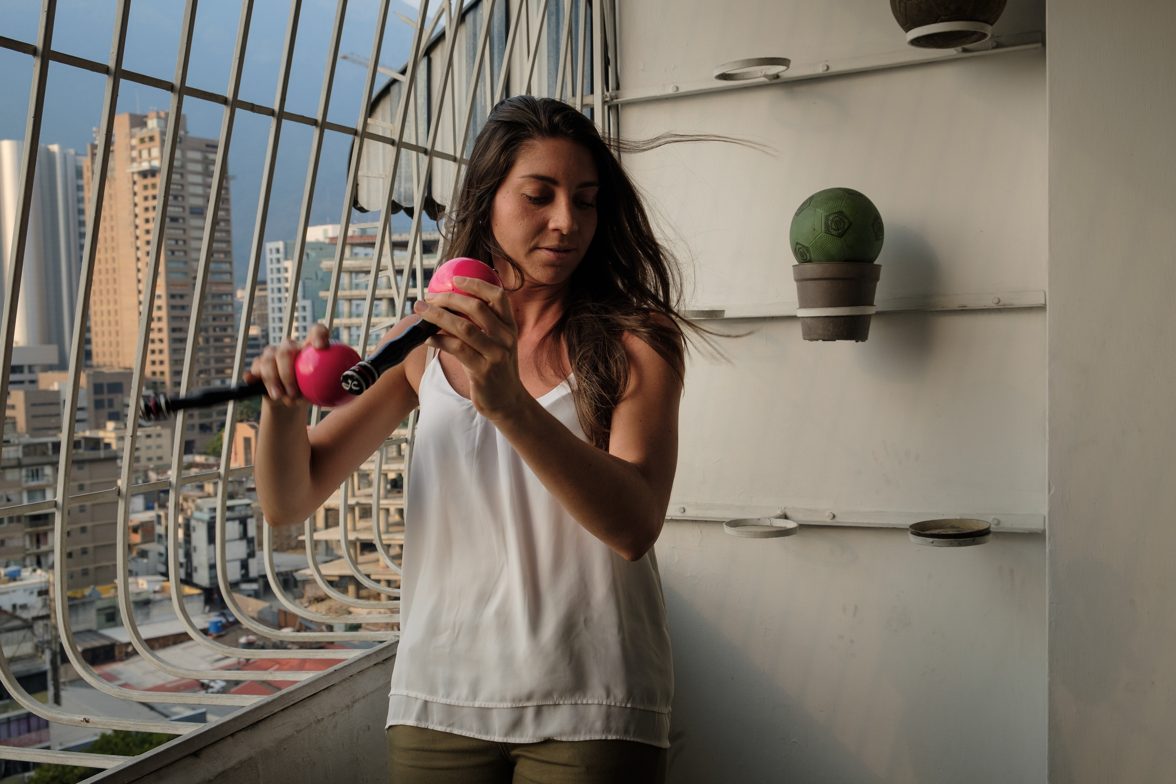 Maria Jose Castejon plays maracas at the balcony of the apartment she lived in. From there she used to be able to tell if protests were going on. The building is in one of the streets where most protests ocurred during 2014 and 2017. She participated in most of them. She moved recently but still uses the place - where her sisters live - to rehearse with the band. Caracas, March 29, 2019