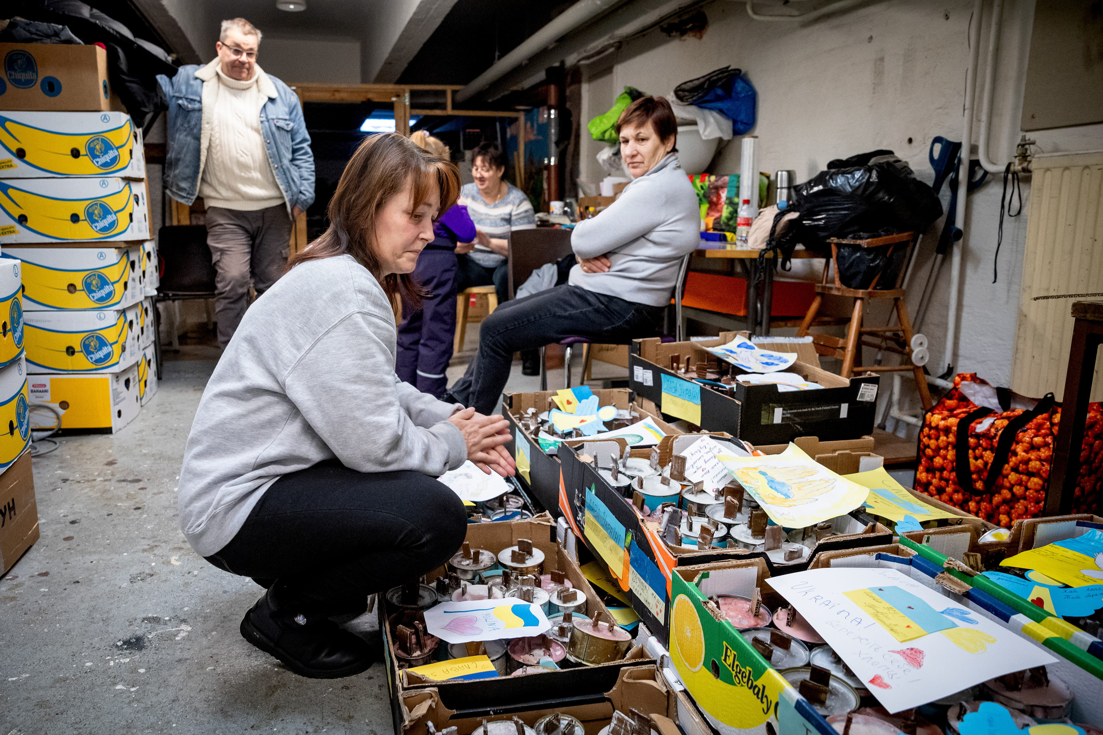 Ukrainalainen Elvira Zadiyakova (edessä) menetti lapsensa venäläisten sotilaiden luoteihin.  Laatikoissa on kynttilöitä, jotka lähtevät Kajaanista juoksuhautoihin ukrainalaissotilaille. (Kainuun Sanomat, 2023)