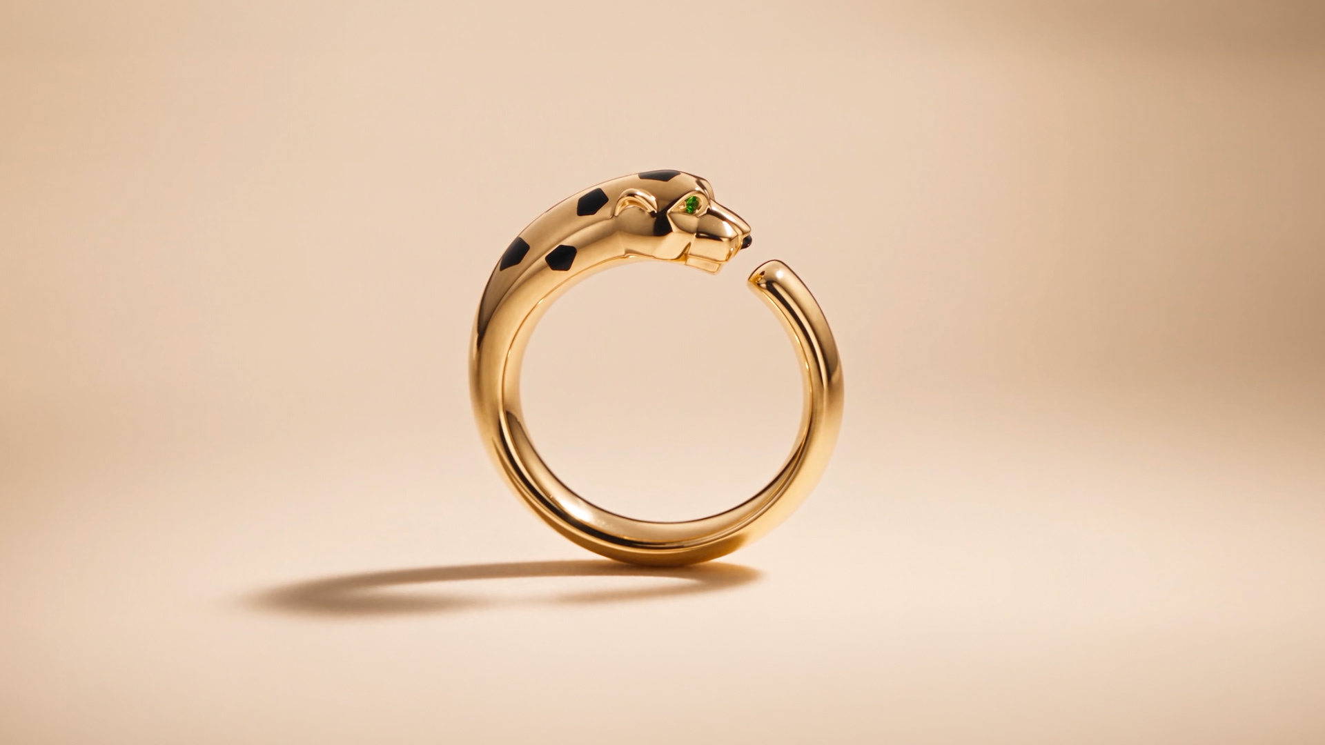 Bague Panthère de Cartier de profil, anneau ouvert en or et tête de panthère tachetée de noir sur fond beige