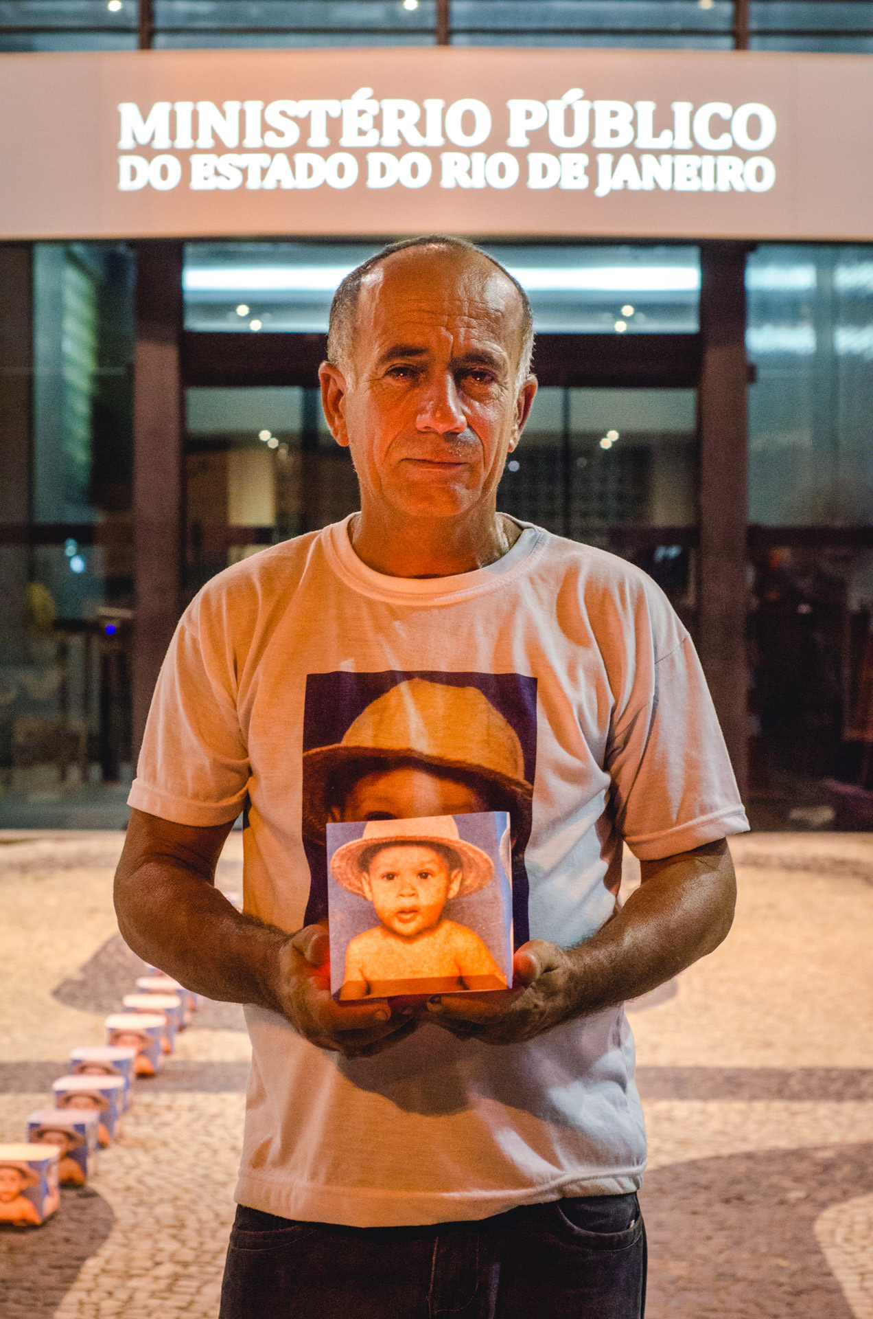 José Luiz holds a photograph of his two-year-old son, Maicon, tragically killed in front of their home by police forces in 1994. Every year, José tirelessly protests in front of Rio's Public Ministry Affairs, fervently seeking justice. His relentless pursuit of justice remains unwavering to this day - Apr 2016 
