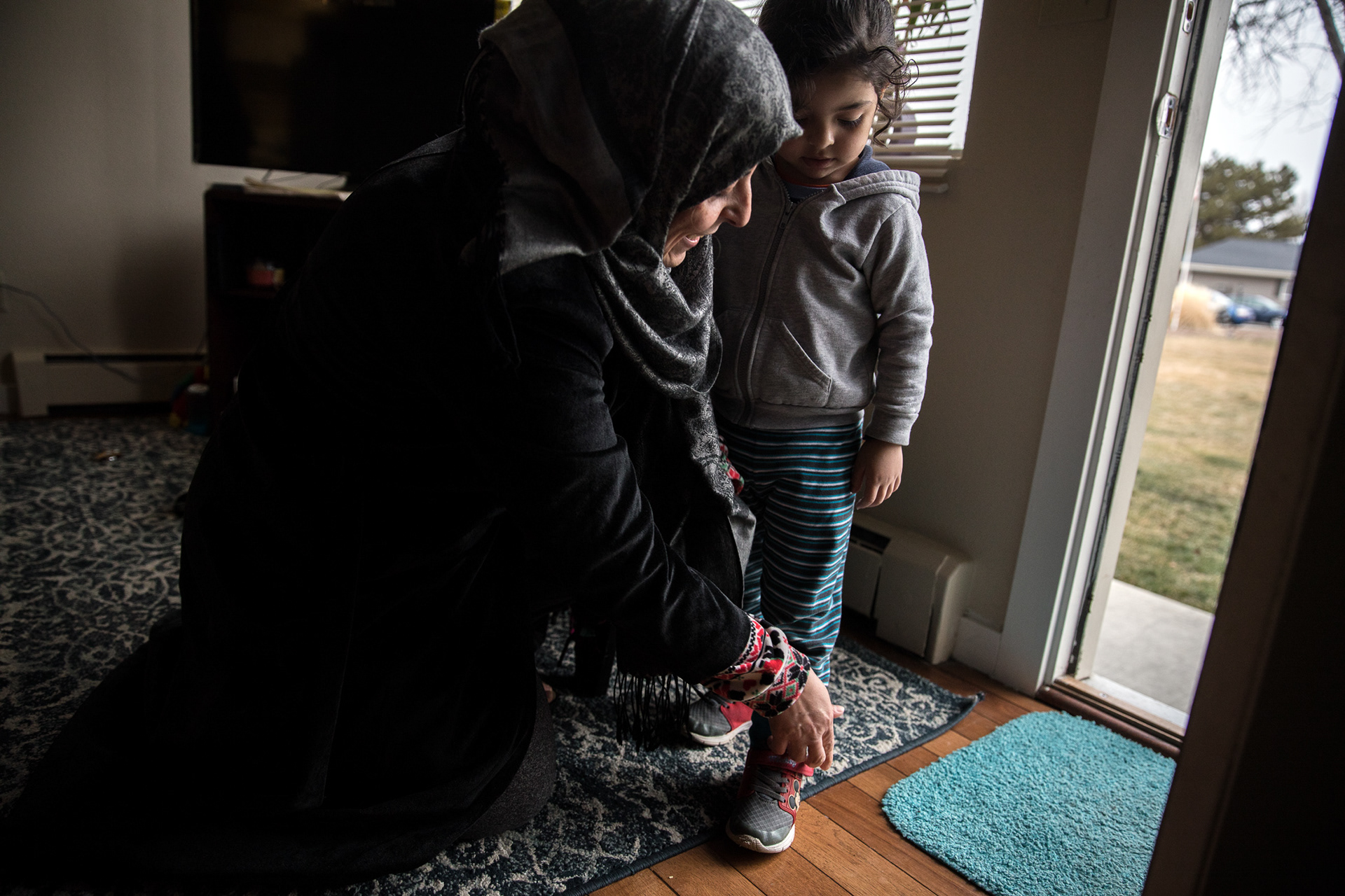 Wejdan Khudhair ties her son Mustafa's shoes before he goes outside to play on Feb. 8 in Boise.