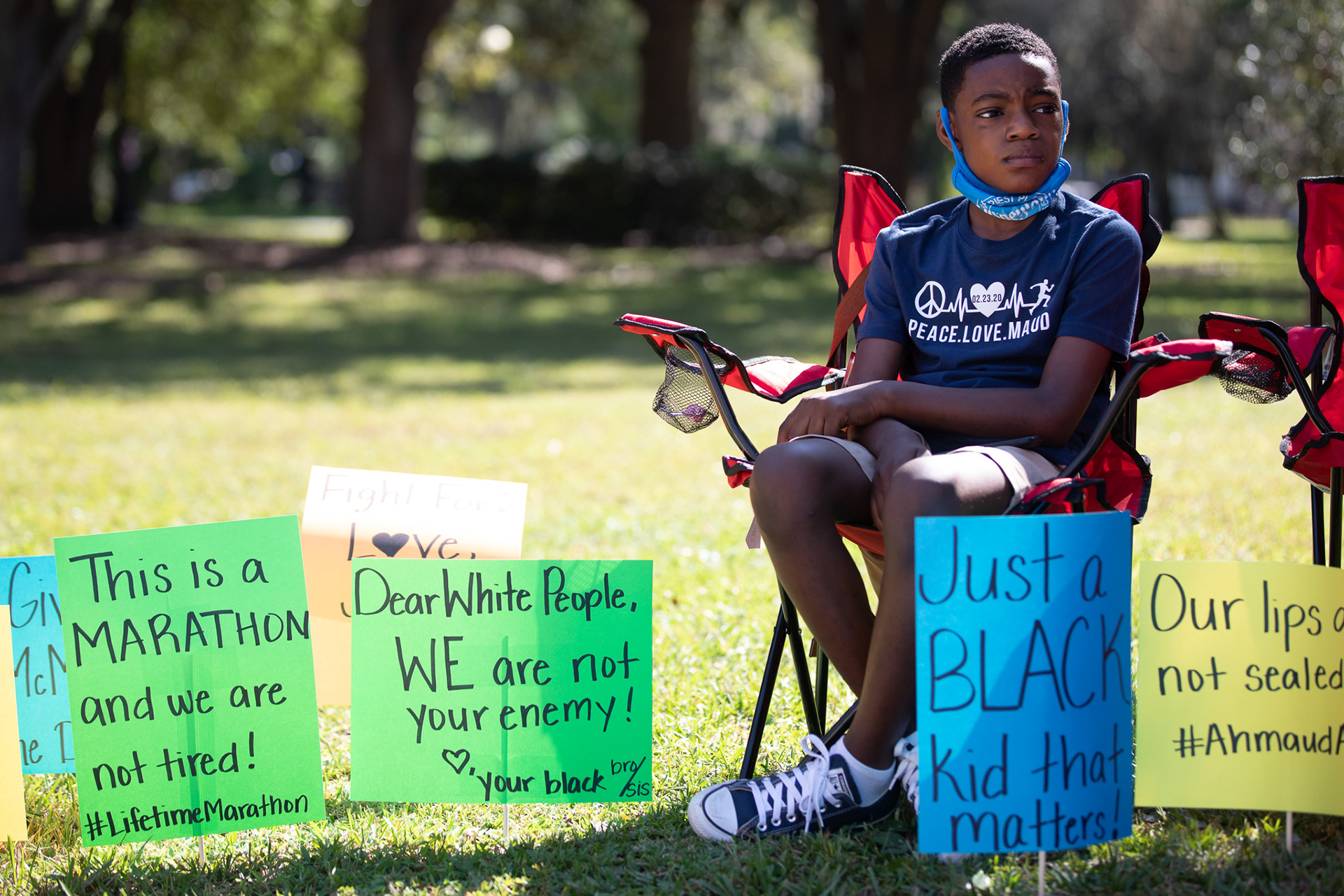 Zyon Thorpe is surrounded by signs in support of Ahmaud Arbery outside of the Glynn County Courthouse during a rally on Oct. 16.