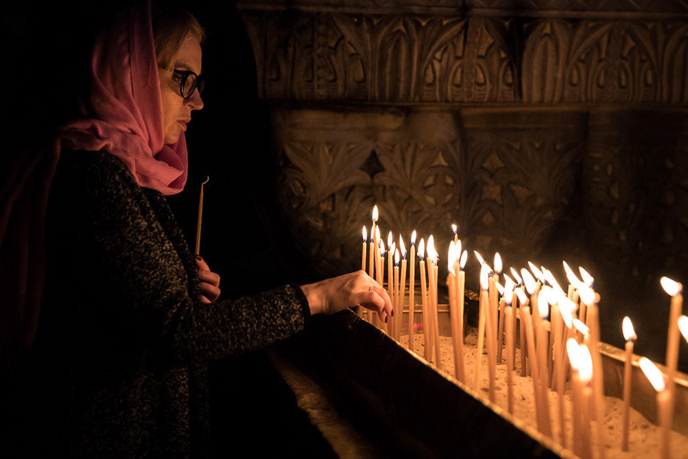 Deep within the heart of the Old City of Jerusalem, up a worn stairway in the Church of the Holy Sepulchre, a woman lights a candle next to the Calvary, traditionally recognized as the site of Jesus’ crucifixion.