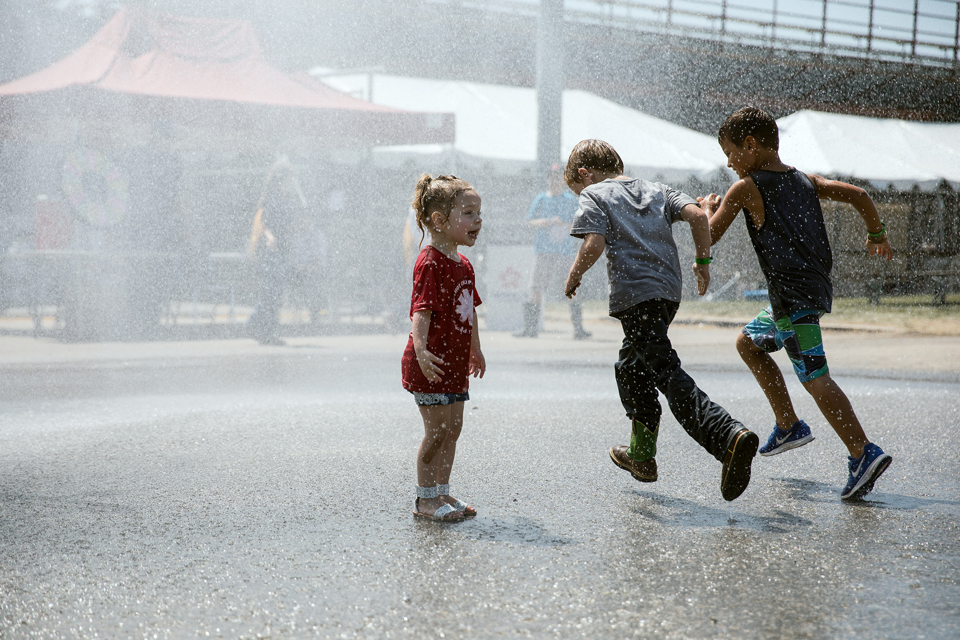 Young children cool off under the spray of a Caldwell fire engine on July 28, 2018, at the Canyon County Fair.