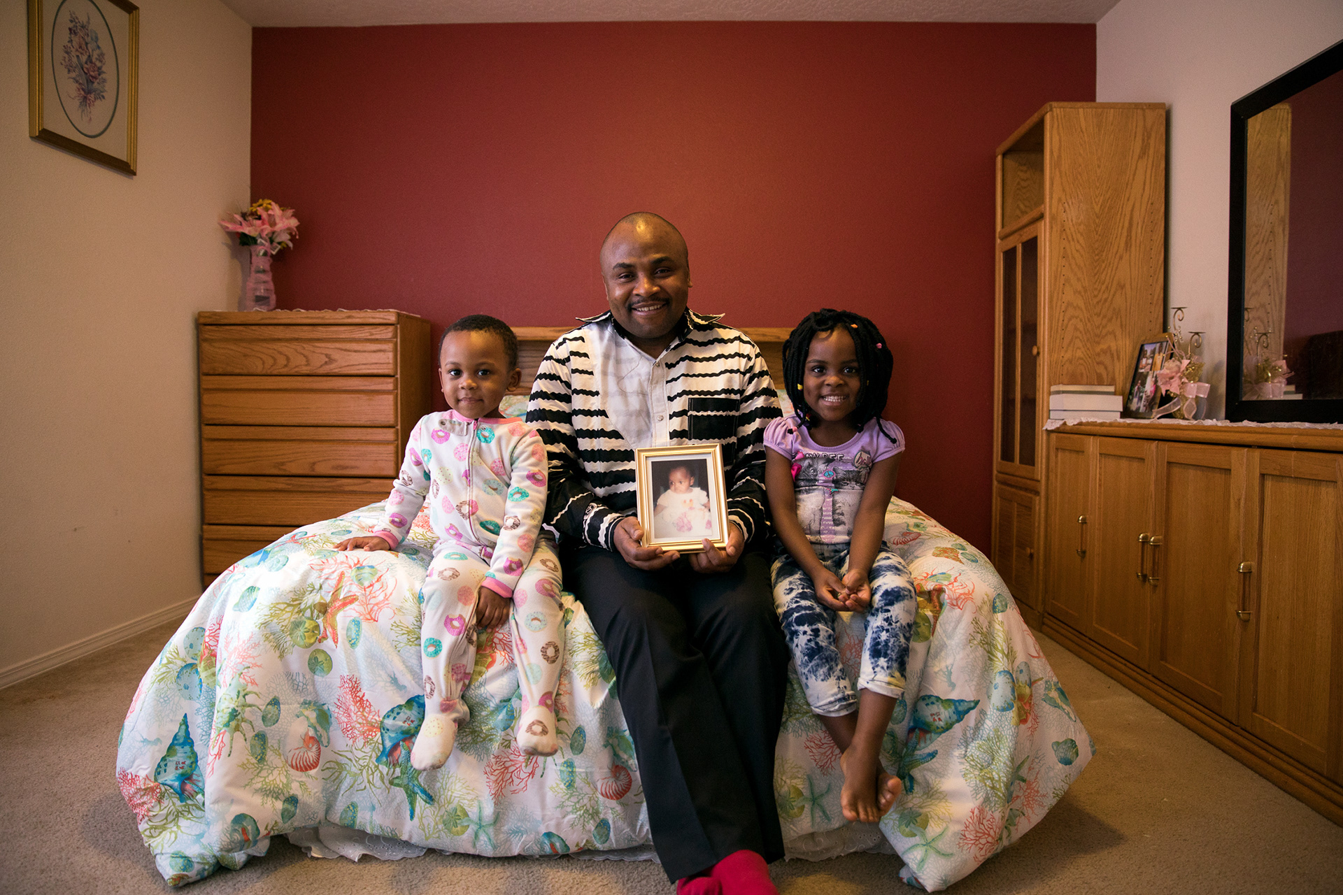 Hagath Mwamba, his son, Joshua, 3, and daughter Angel, 5, sit on the bed they have prepared for Ornelie, 18, when she arrives to the United States, on Feb. 6 in Boise.