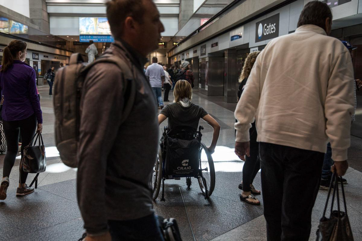 Nikeela Black navigates the busy train stop at Denver International Airport on Oct. 18 during a training session to practice going through security in a wheelchair.