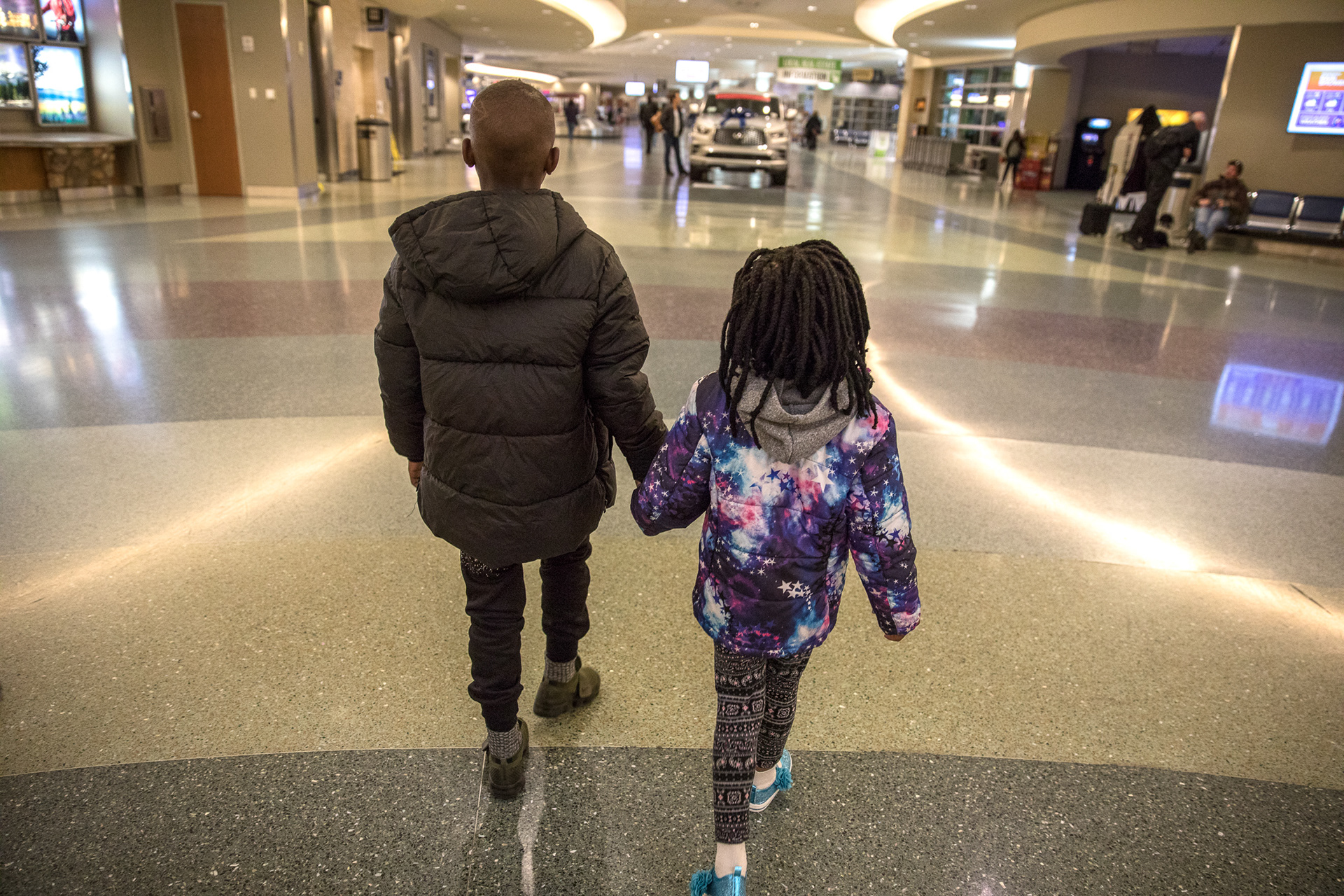 Patient, 9, holds his sister's hand as they search for his luggage in the Boise Airport on March 6.
