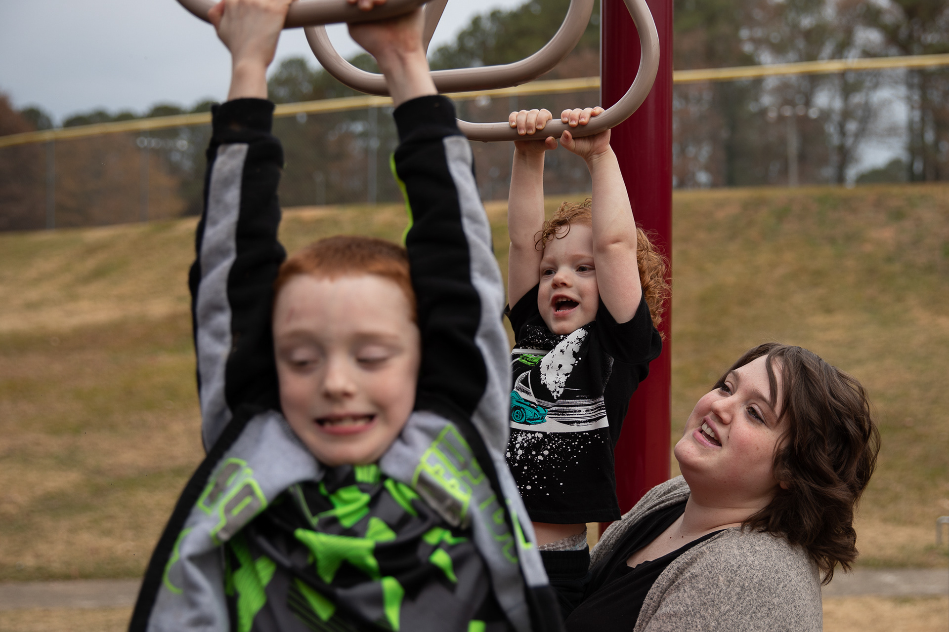 Hannah Ochoa lifts her 2-year-old son, Wyatt, up to the monkey bars so he can follows his older brother Kye across the playground at Shaw Park in Marietta.