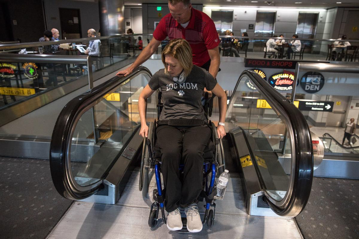 Nikeela Black practices going down escalators with the help of Craig Hospital staff at the Denver International Airport on Oct. 18.