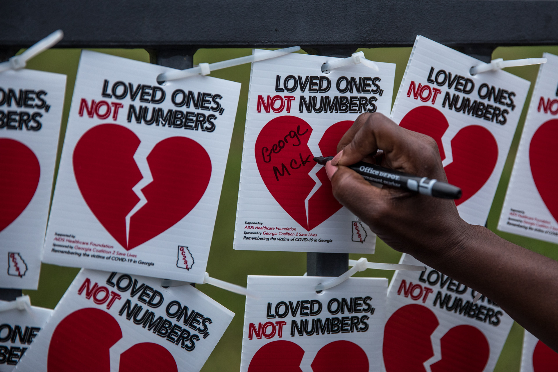 Family of loved ones lost to COVID-19 along with volunteers string up paper hearts to memorialize the victims outside of the National Center for Civil and Human Rights in downtown Atlanta Aug. 27.