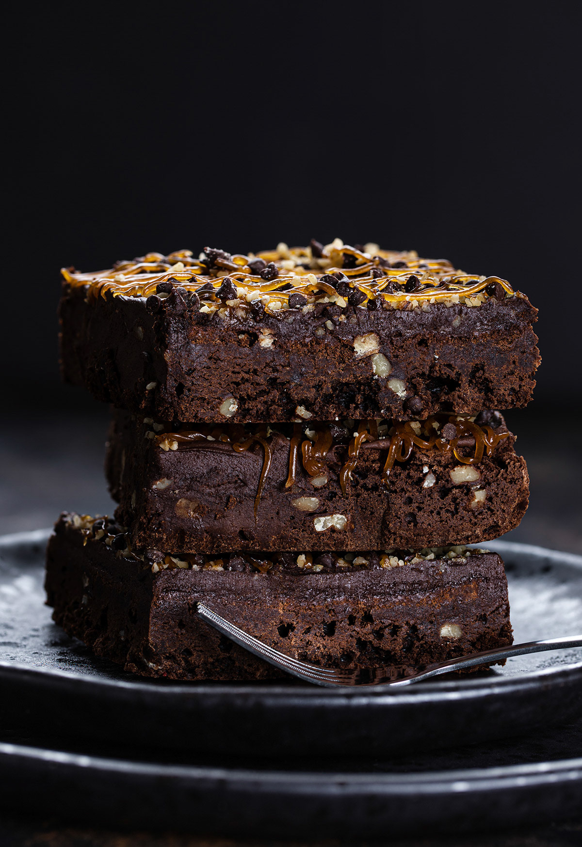 Chocolate fudge brownies stacked on a plate.