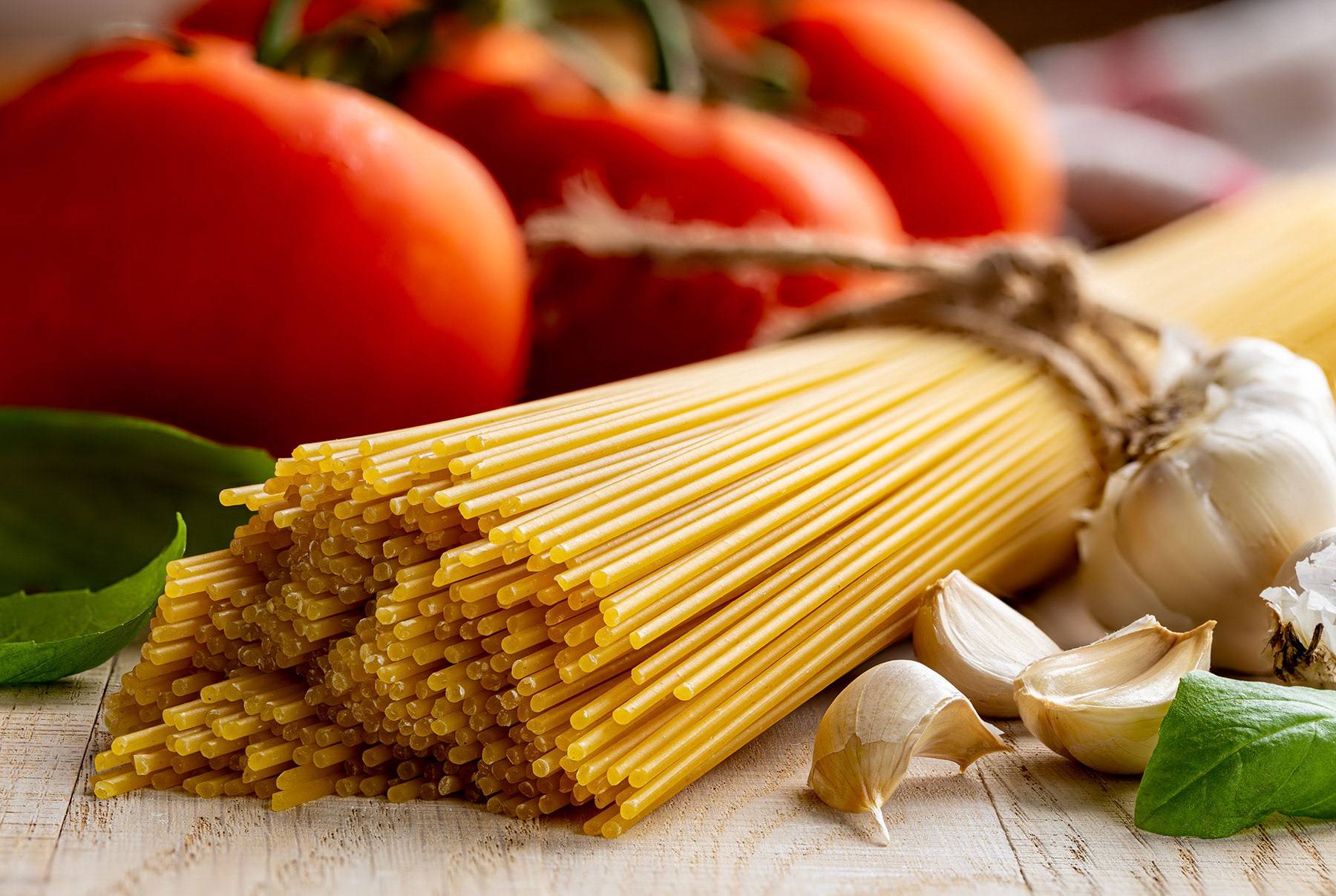 Spaghetti pasta with fresh tomatoes in background