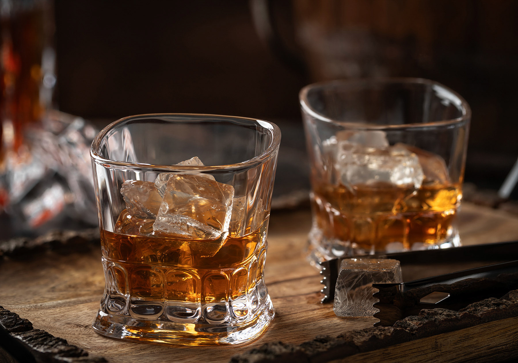 Glasses of whiskey with ice on wooden tray