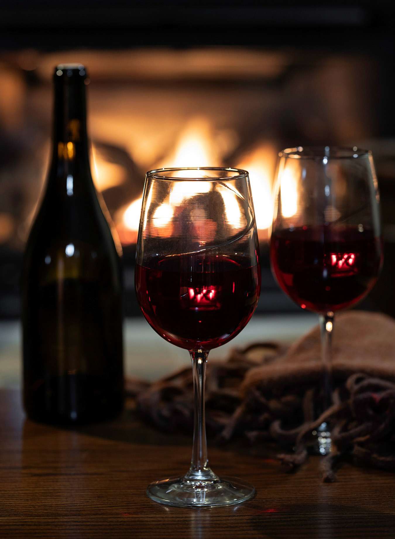 Glasses of red wine with fireplace in background
