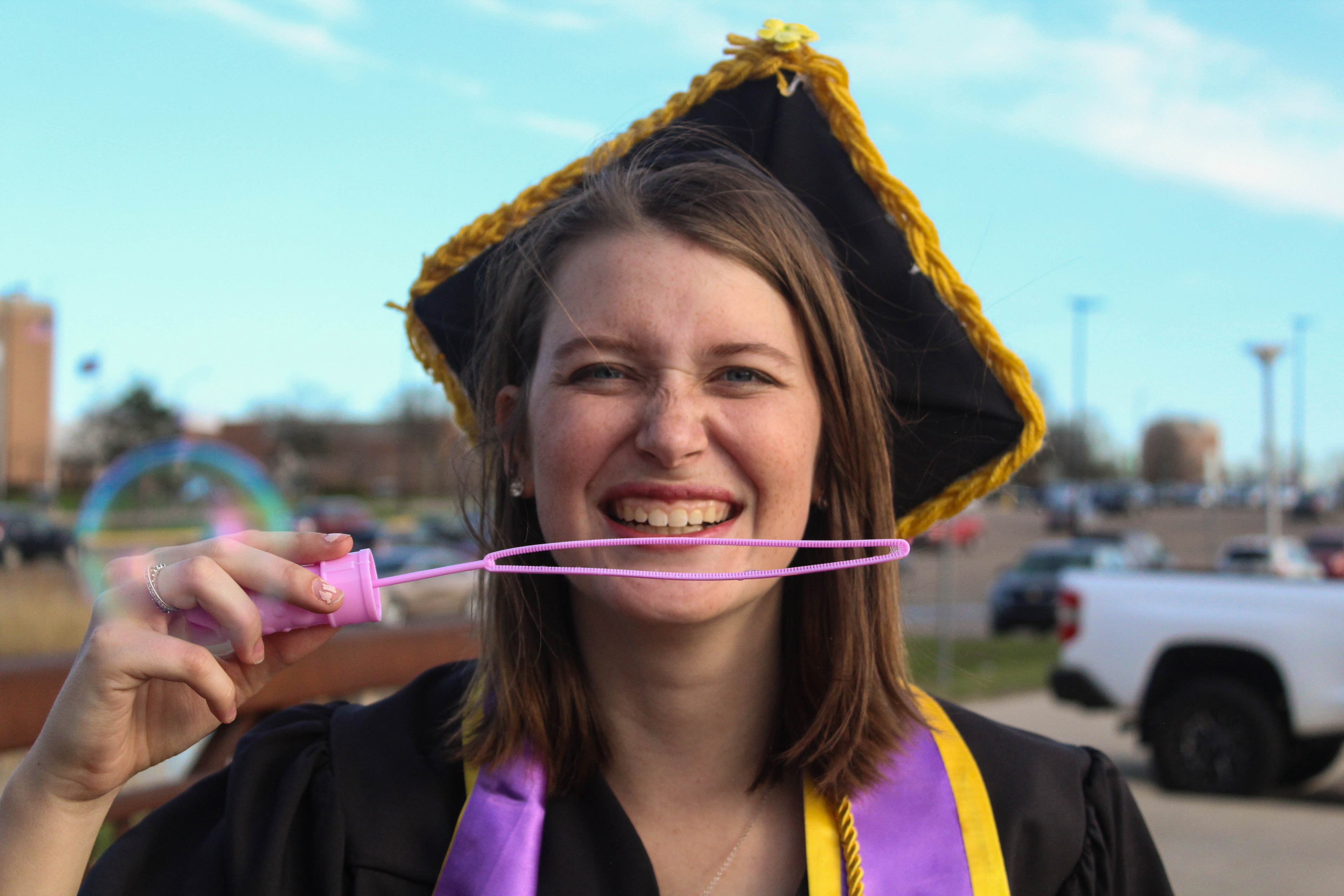 April 2019 | Graduation portrait of Katie blowing bubbles at the camera