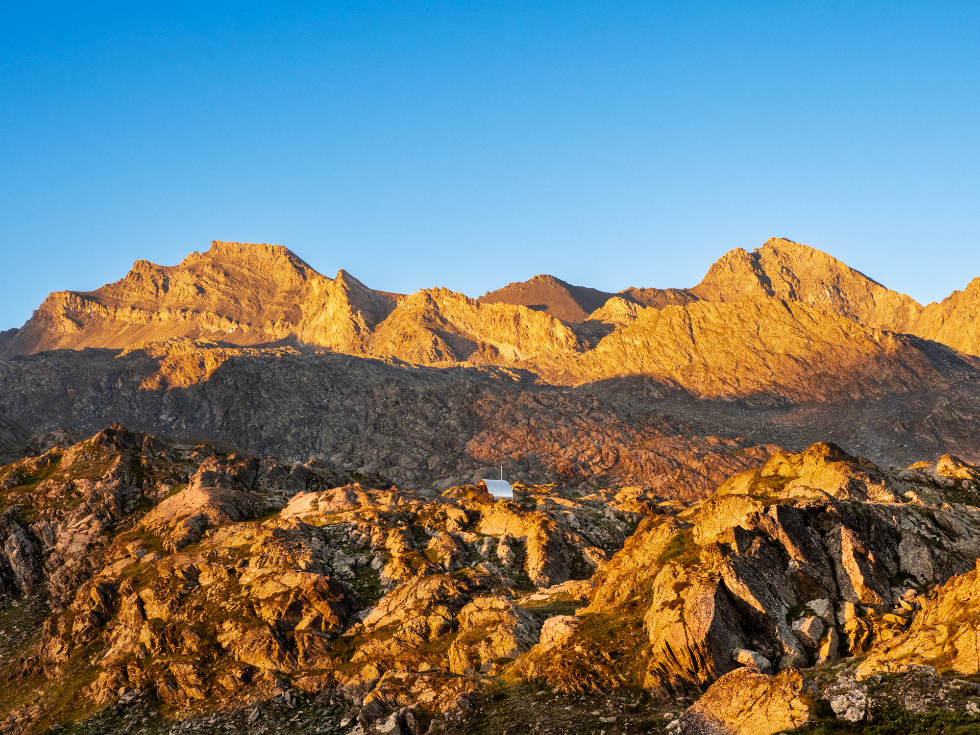 Il Bivacco Enrico Olivero all'alba dinnanzi al Monte Salza e al Mongioia