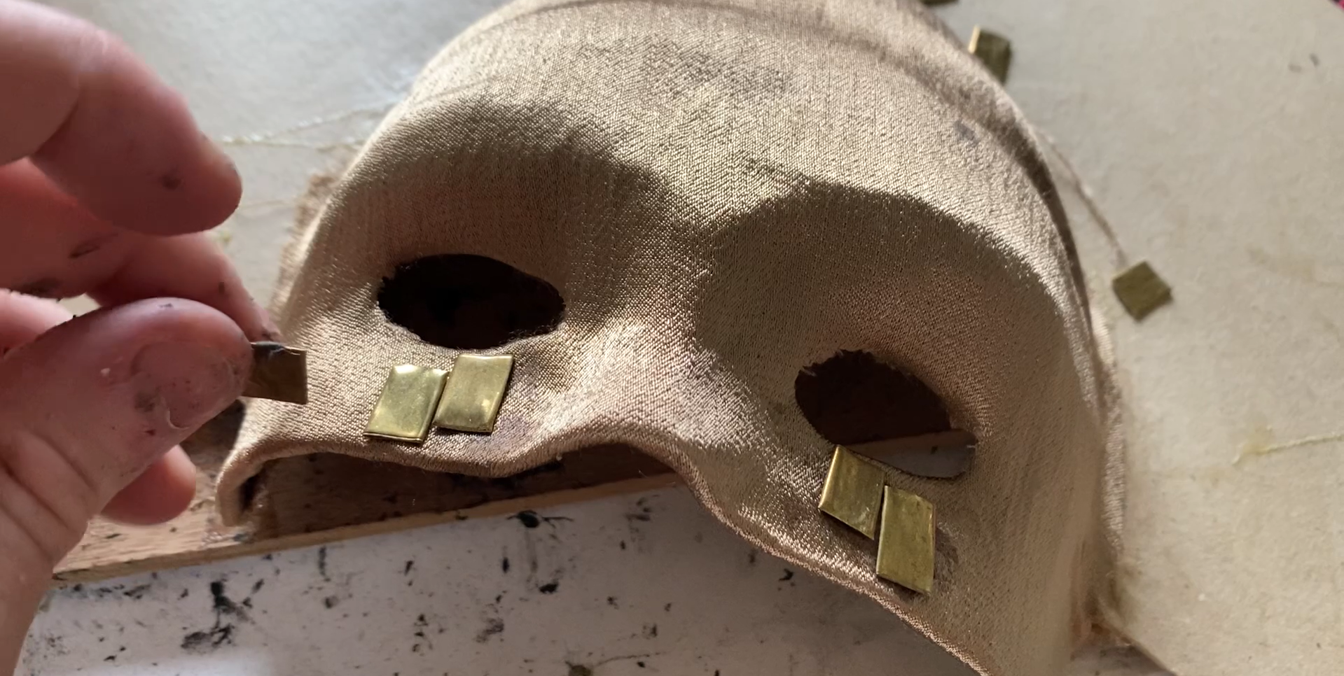 (2022). Attaching flattened brass to Nero's mask. [Photograph].