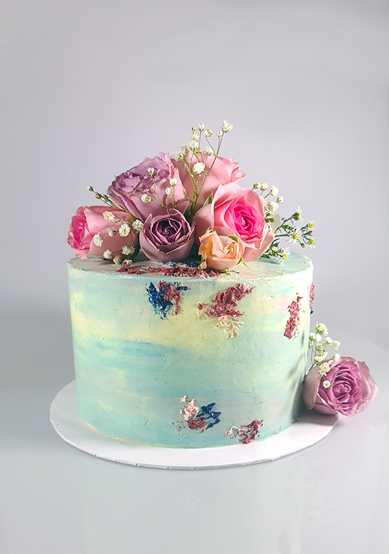 Ribbon cake covered with butter cream. Decorated with sprinkles. Topped off with fresh flowers