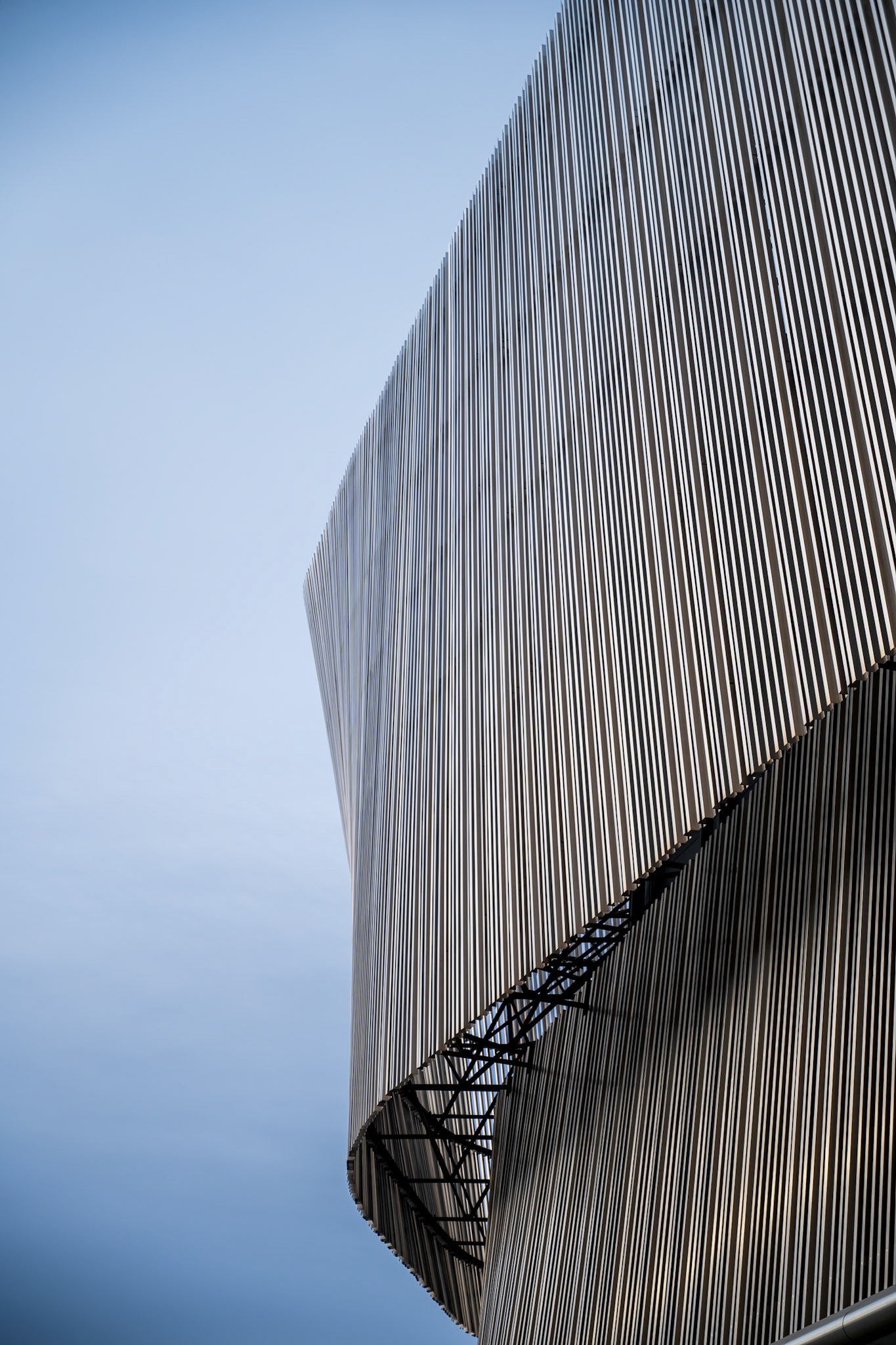 A striking modern building with a unique structural design stands tall against a cloudy sky.