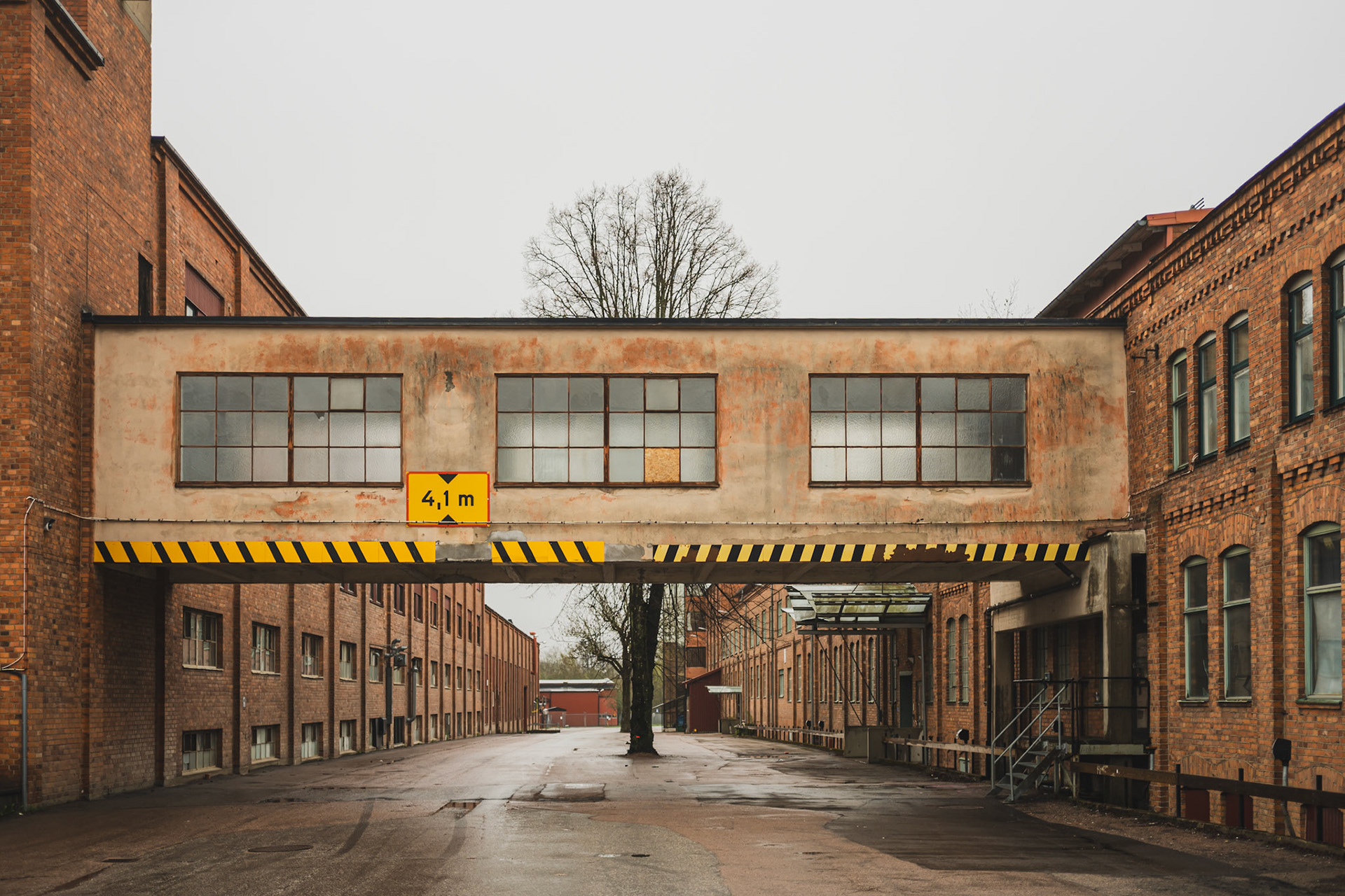 An overcast day reveals an abandoned industrial building with a height limit sign of 4.7 meters hanging over the entrance.