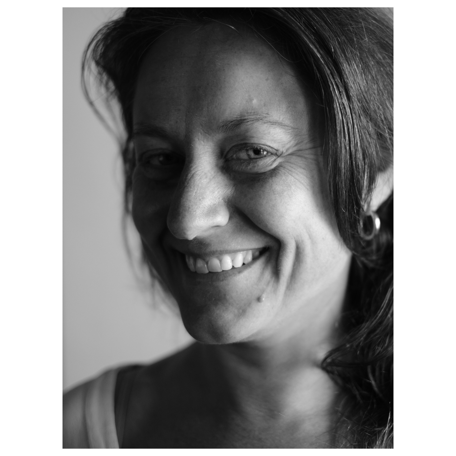 Ritratto fotografico di una donna sorridente con occhi verdi immersa in una luce che arriva da una finestra
