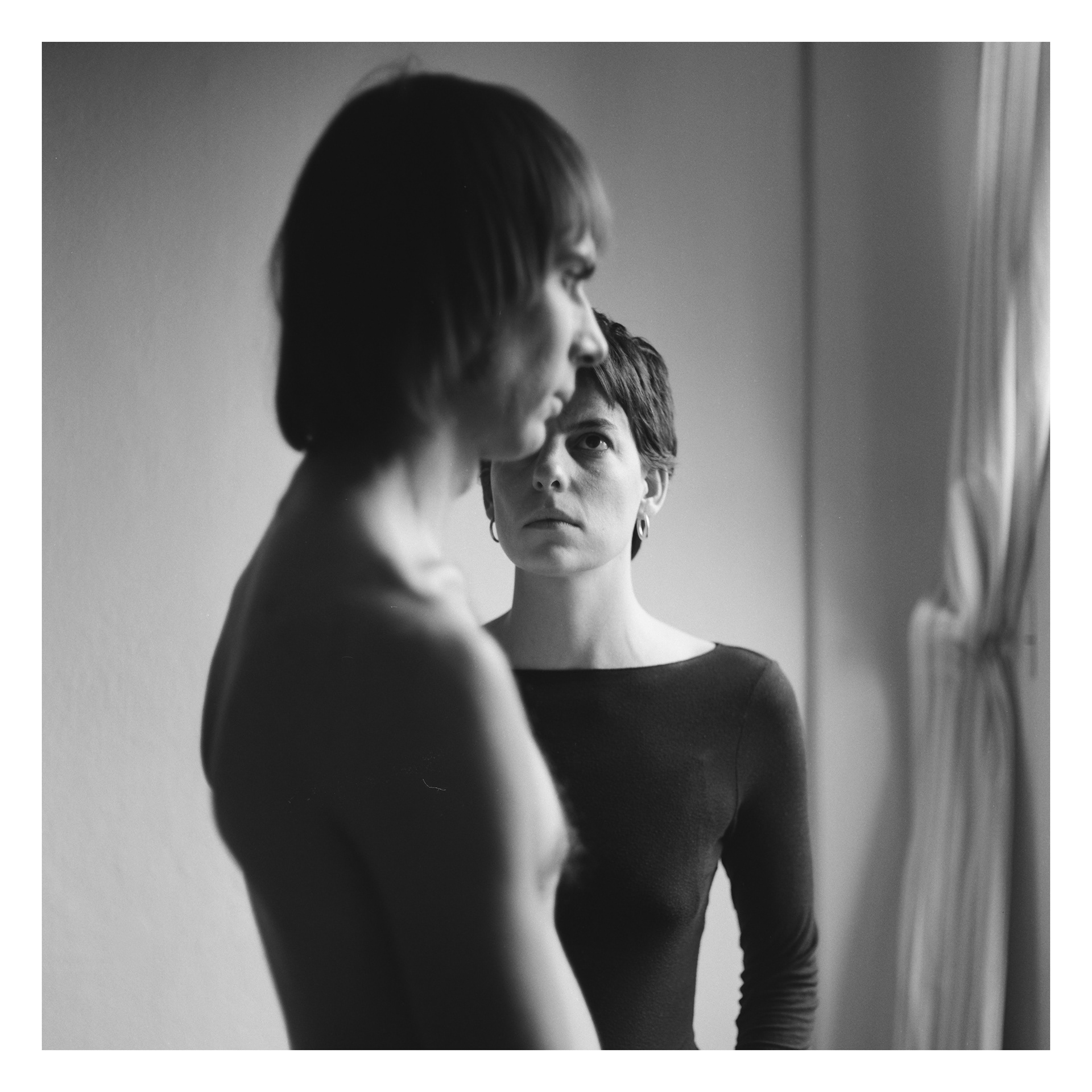 Foto in bianco e nero in luce naturale di Alessio a torso nudo di profilo con dietro una giovane donna che lo guarda - progetto fotografico di Andrea Palumbo